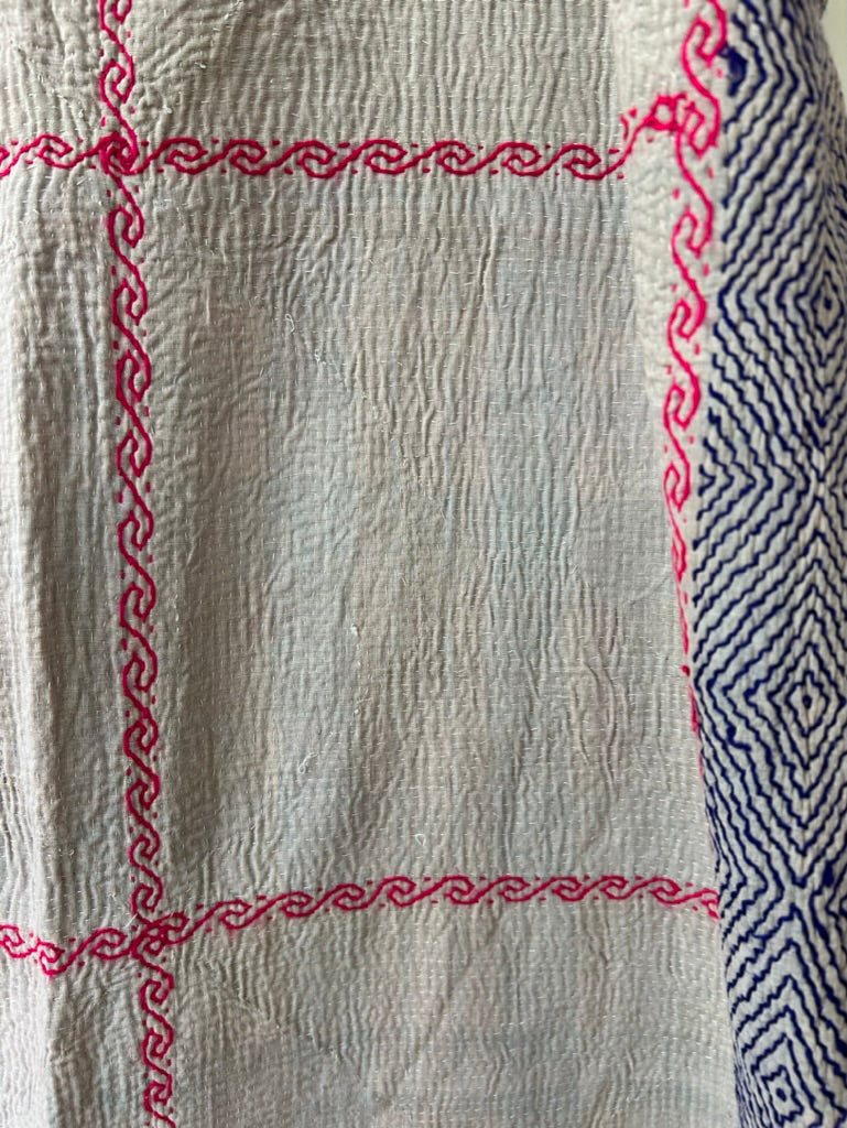 Textile with red and blue embroidery on a beige background
