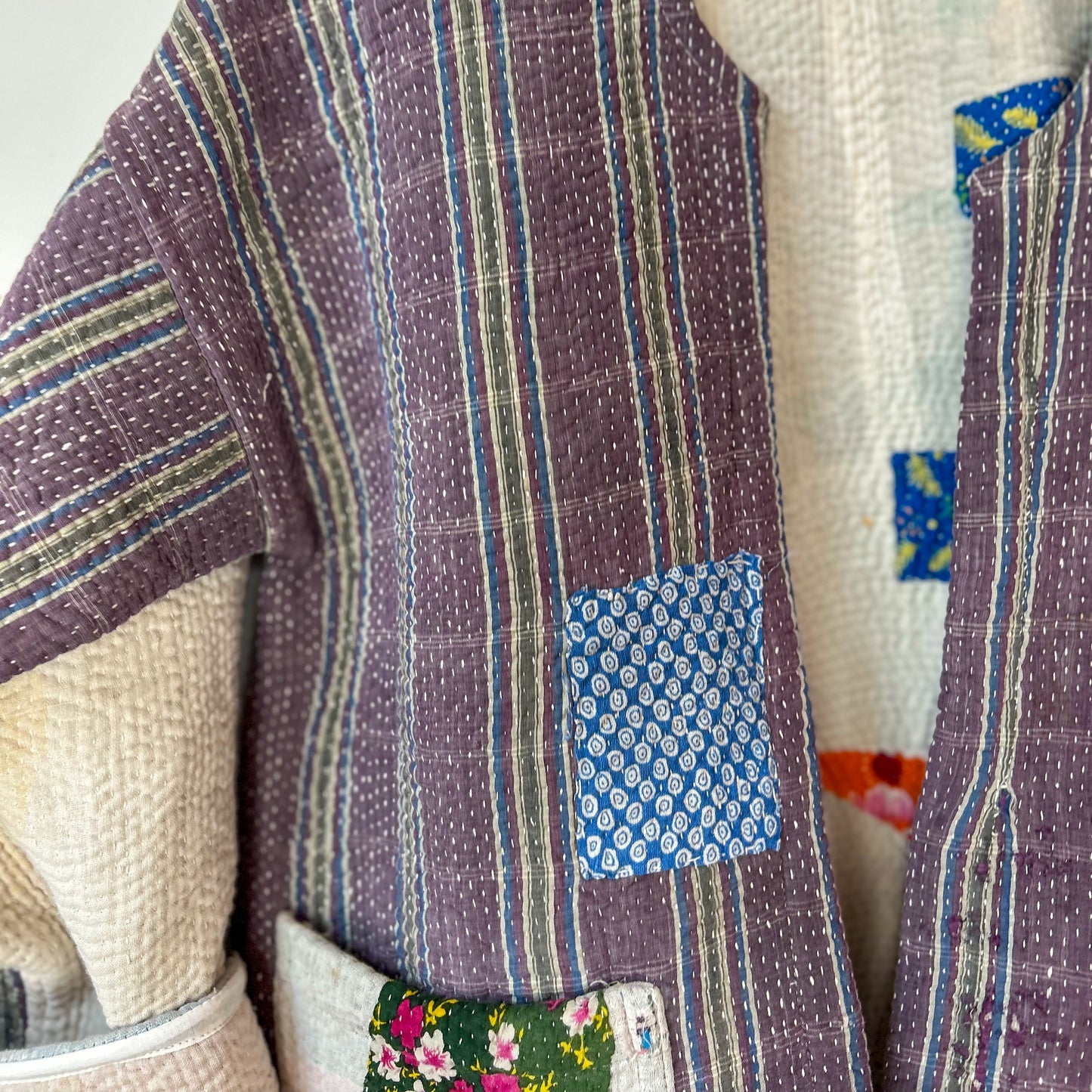 Close-up of a quilt with multicolored patterns and patches. Vintage-kantha-jacket-handmade-unique-mauve-34-sleeve-detail-collar