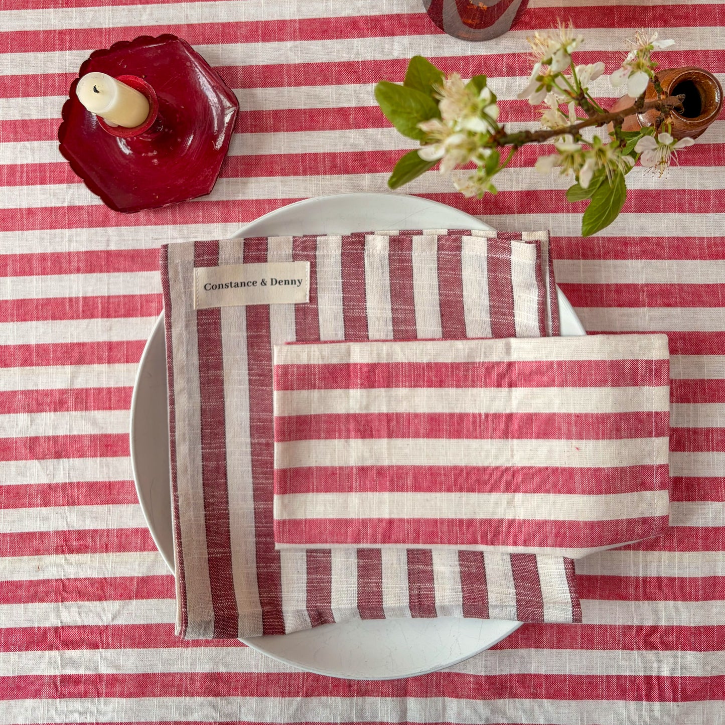 Red and white striped tablecloth with a folded napkin on a red and white checkered tablecloth.