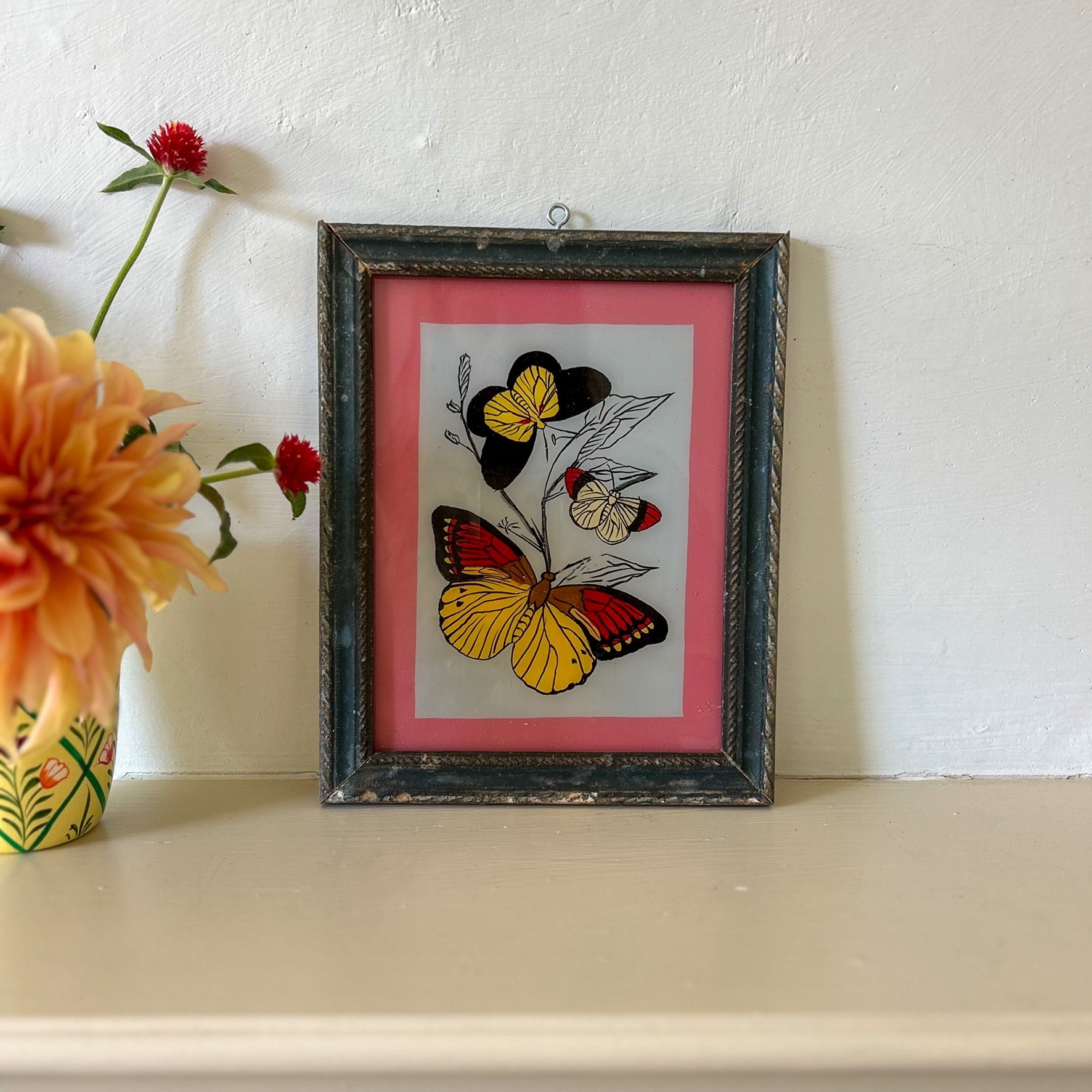 Framed artwork of butterflies on a pink background with flowers beside it. constance-and-denny-indian-reverse-glass-painting-boxed-packaging-hand-painted-artisan-art-butterfly