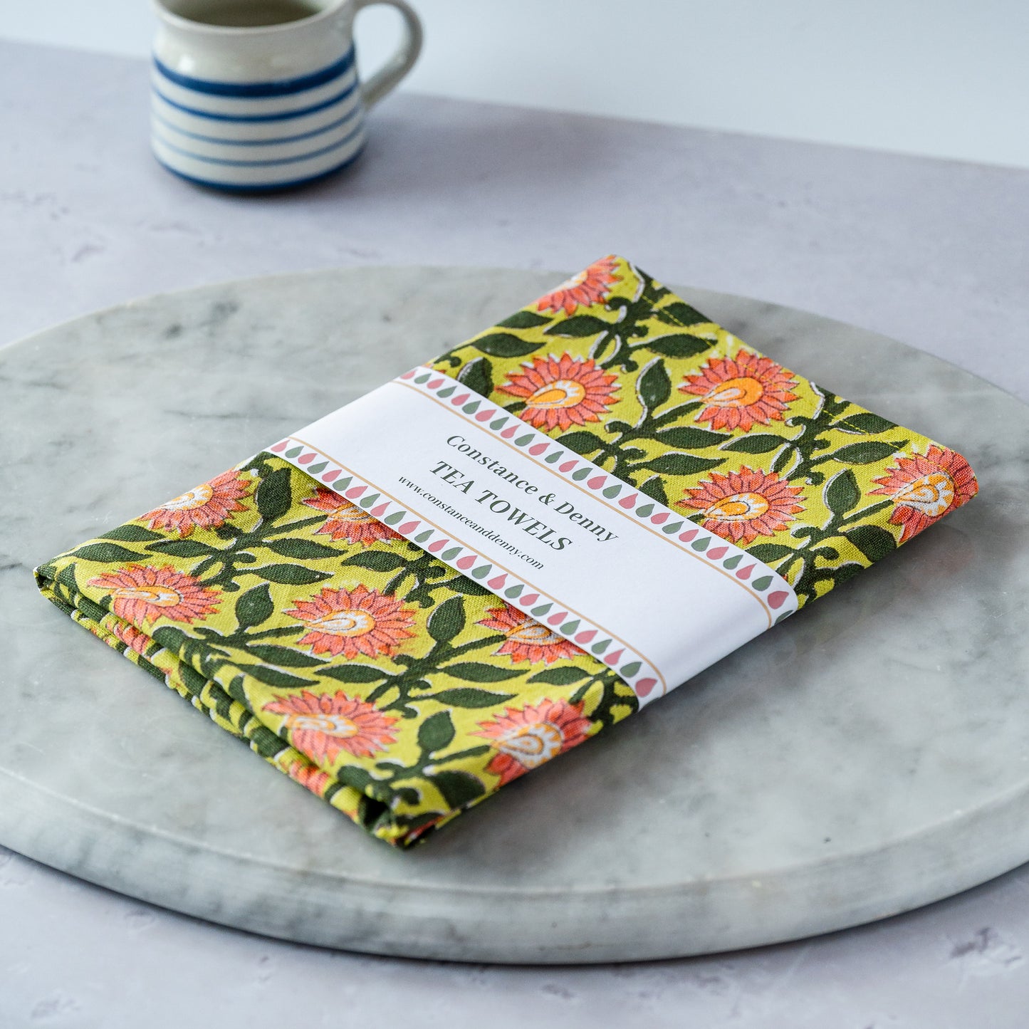 Pack of floral tea towels on a marble surface with a mug in the background