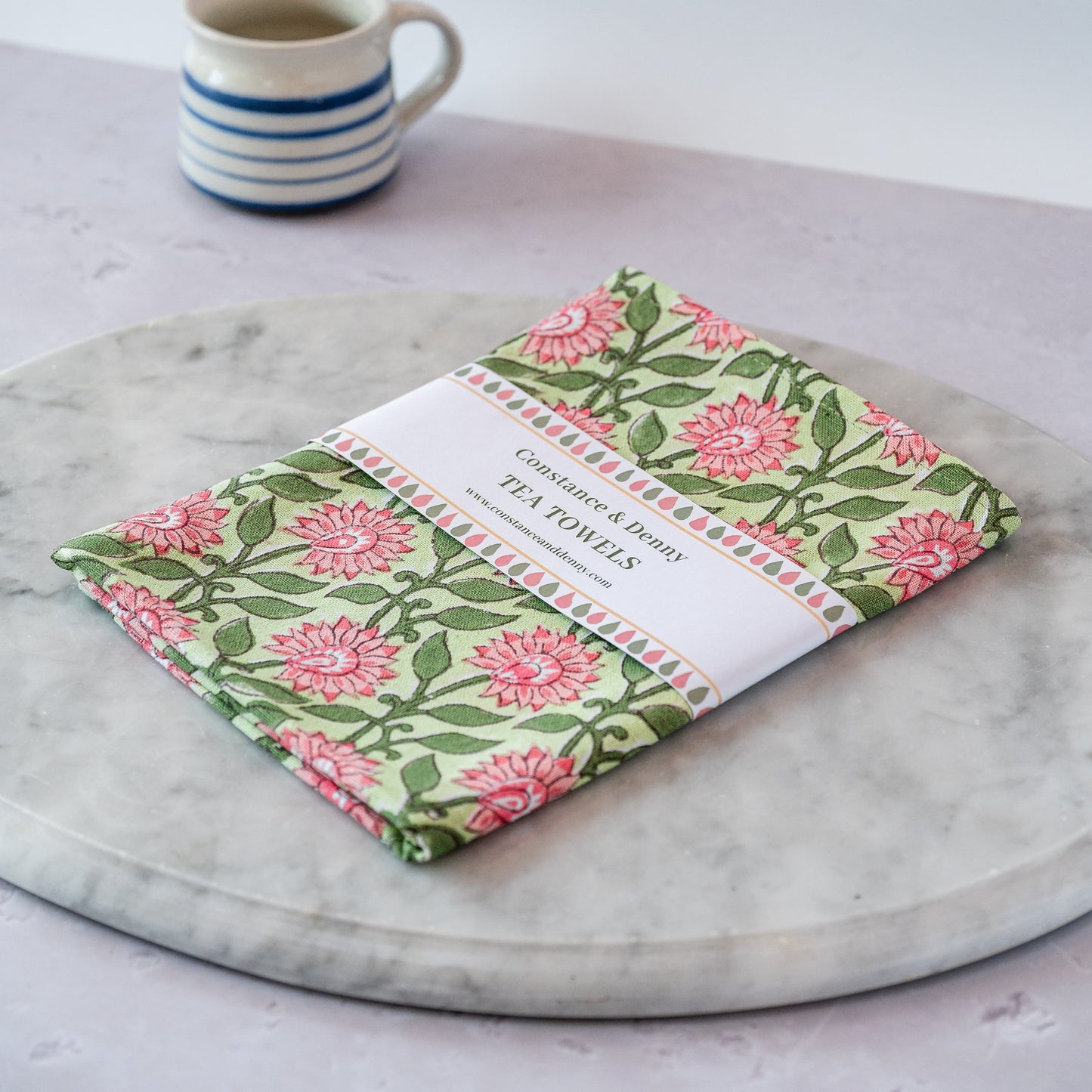 Floral tea towel on a marble surface with a cup in the background