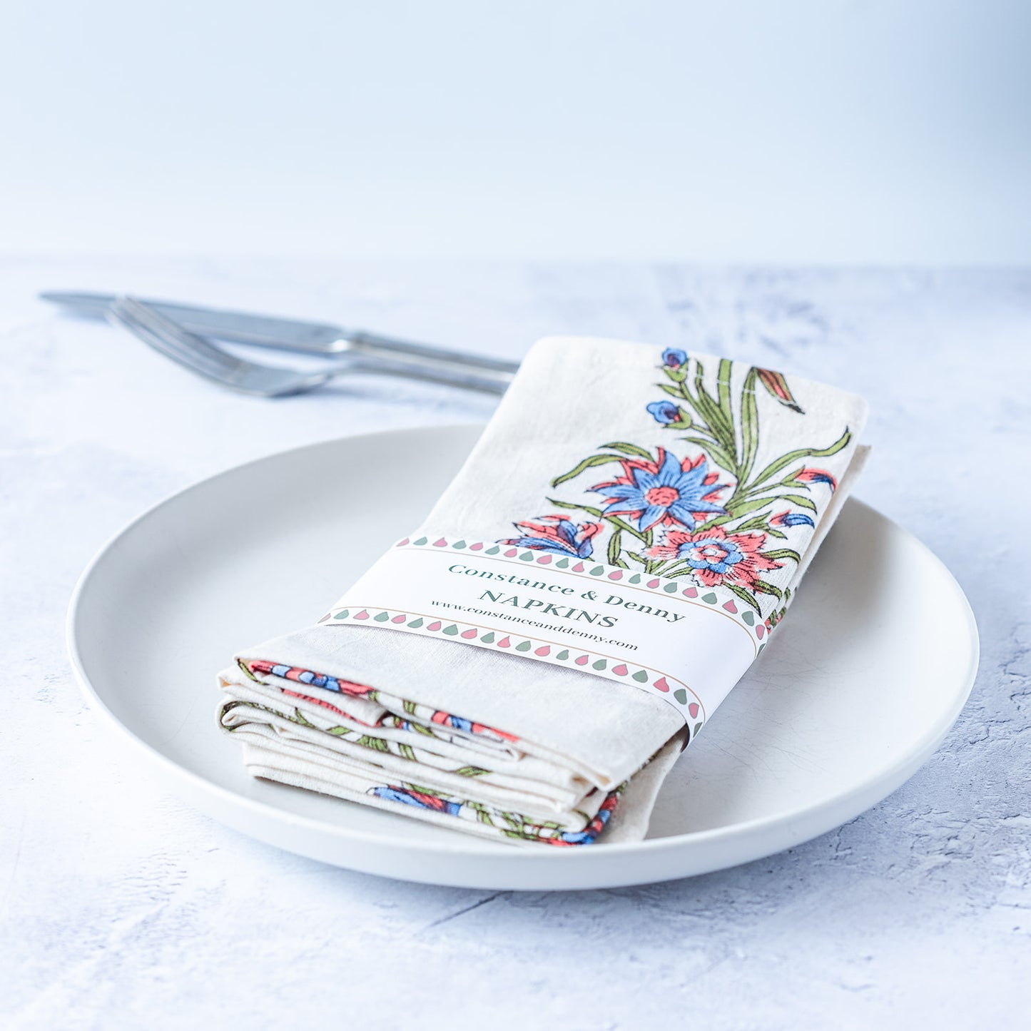 Set of floral-patterned napkins on a white plate with a light blue background.block-printed-set-of-4-napkins-FLORAL-WILDFLOWER
