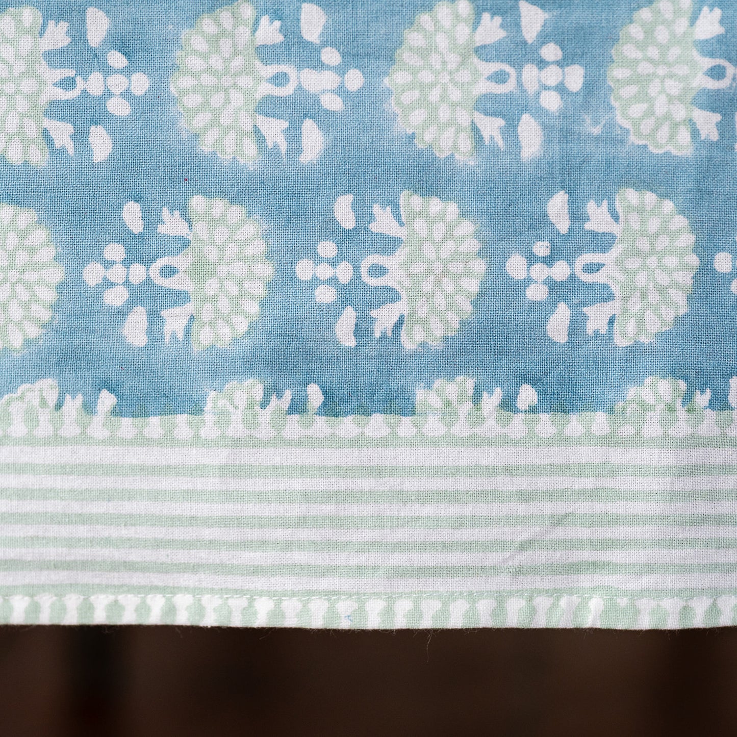 Fabric with a pattern of white and light green flowers on a blue background