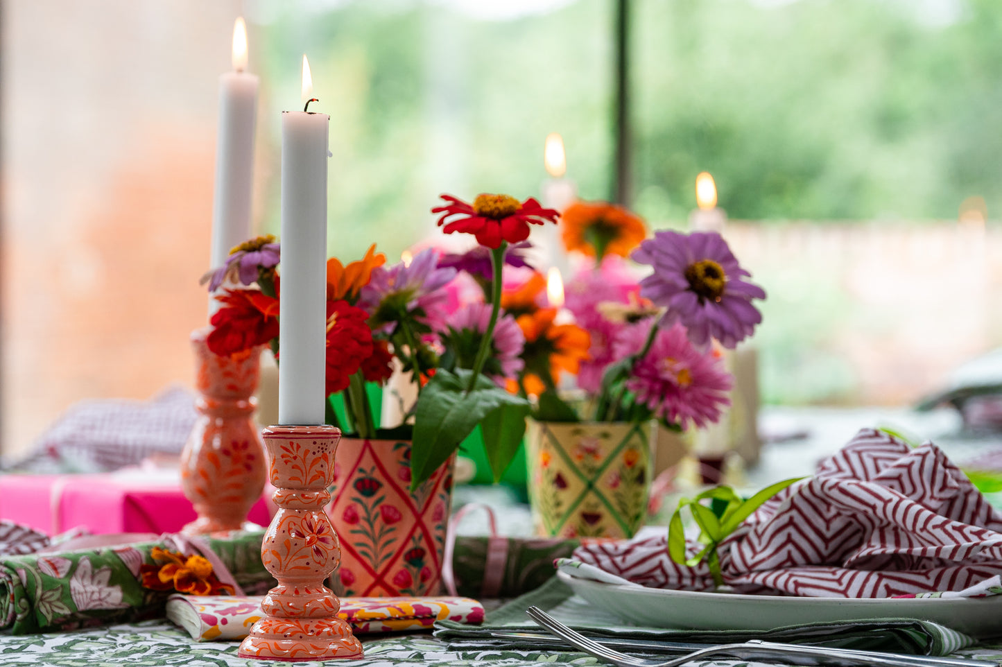 Decorative table setting with candles, flowers, and a colorful napkin.