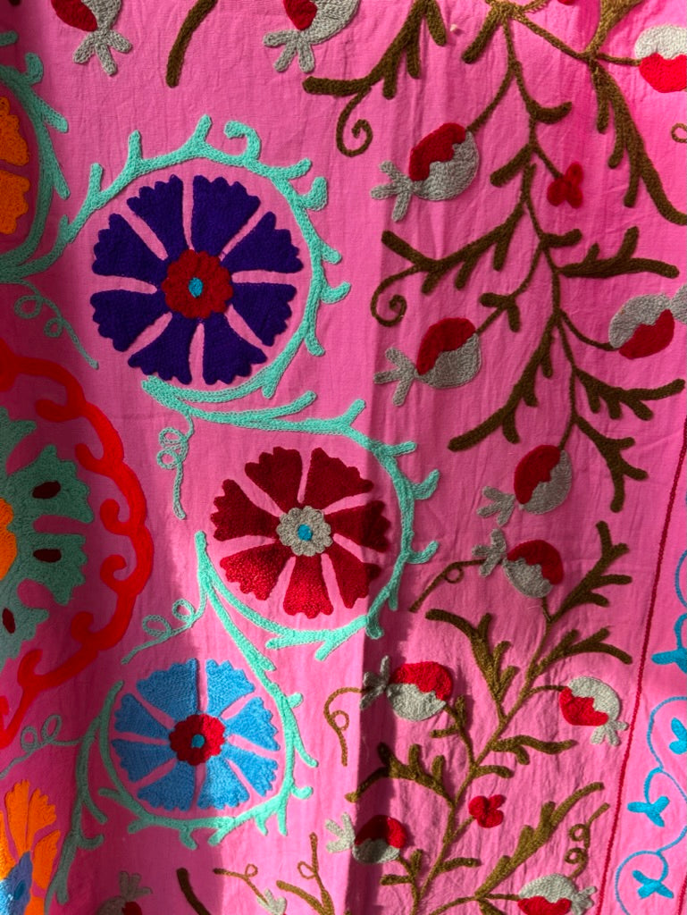Close-up of pink fabric with colorful floral embroidery