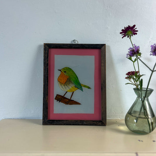 Framed artwork of a colorful bird on a table with a vase of flowers. indian-glass-painting-reverese-robin