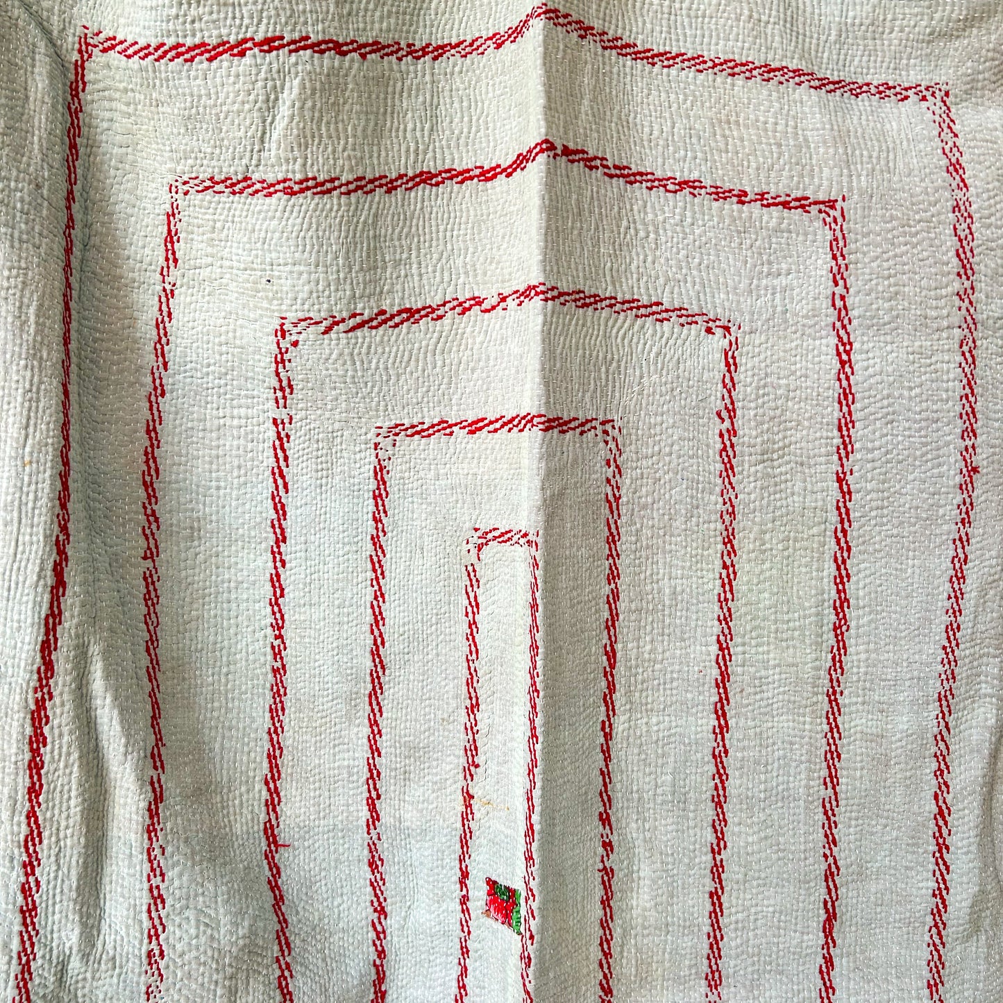 Close-up of red embroidered patterns on a beige fabric background. kantha-vintage-2027 - hand-made-blanket-throw-textiles-wall-hanging