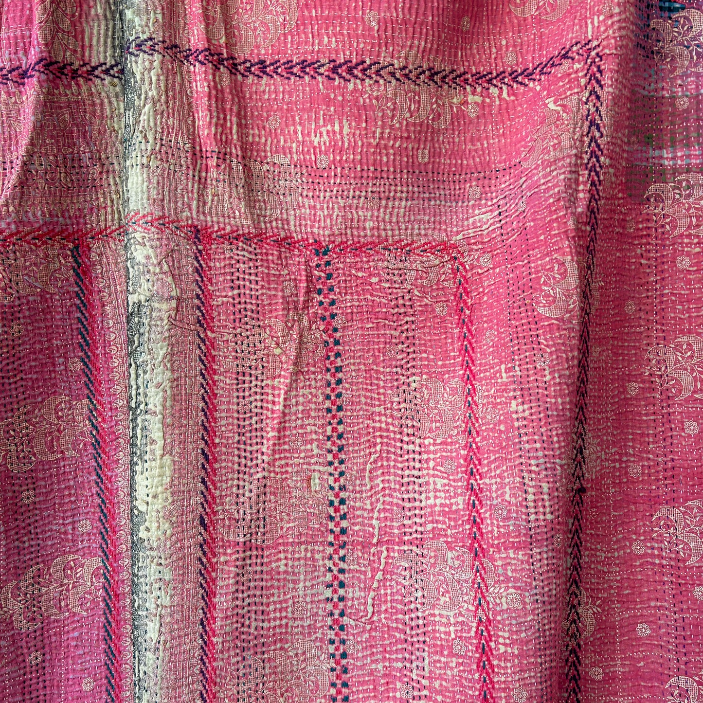 Close-up of pink fabric with intricate patterns and embroidery. kantha-vintage-2028- hand-made-blanket-throw-textiles-wall-hanging