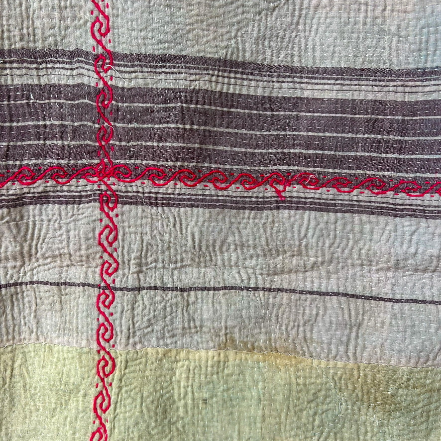 Textile with red embroidery on a striped fabric background