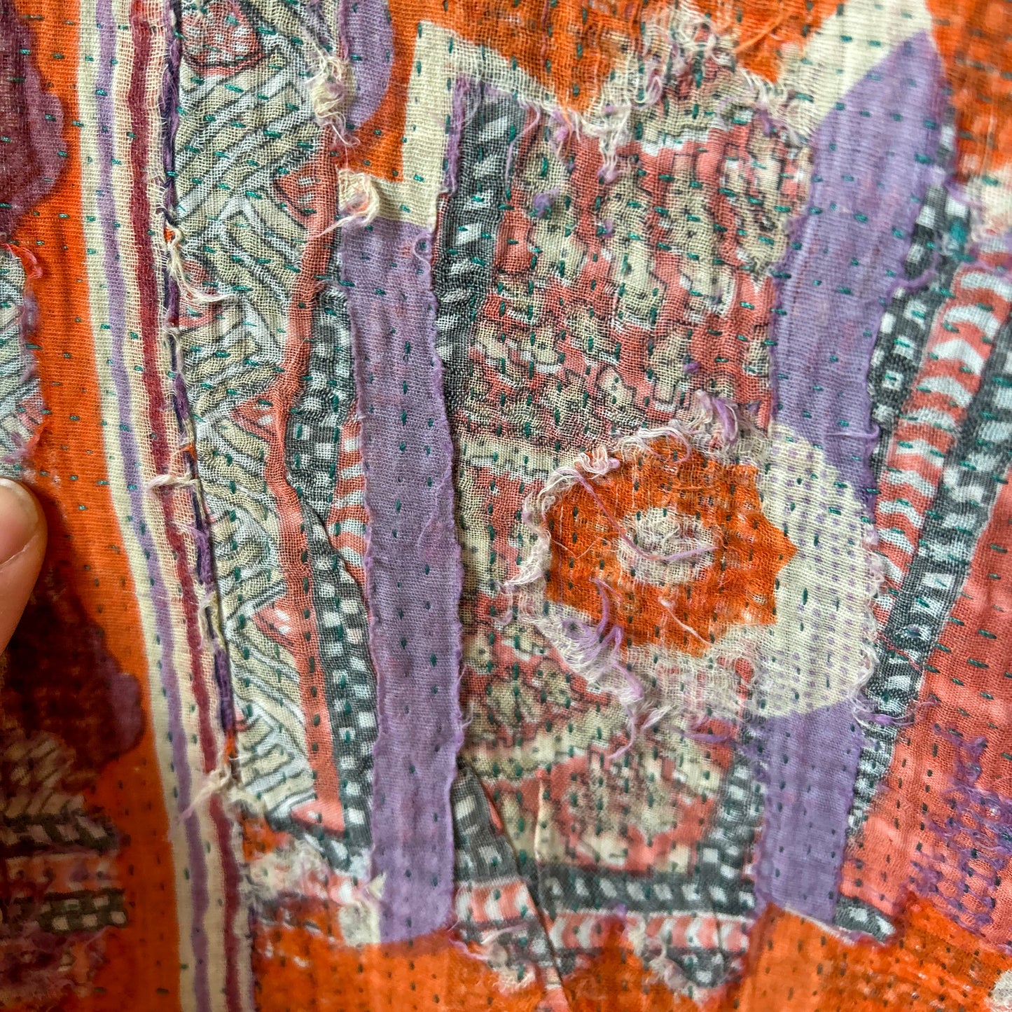 Close-up of a textured fabric with intricate patterns in orange, purple, and green.