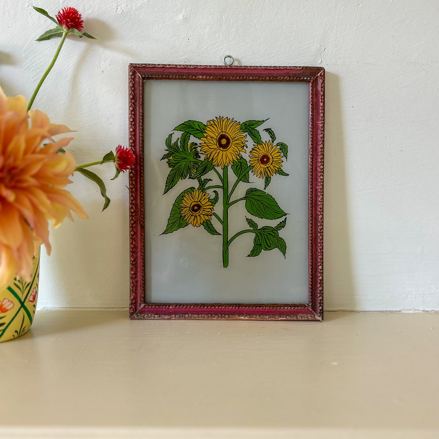 Framed embroidered artwork of sunflowers on a white surface with flowers in the background. constance-and-denny-indian-reverse-glass-painting-boxed-packaging-hand-painted-artisan-art