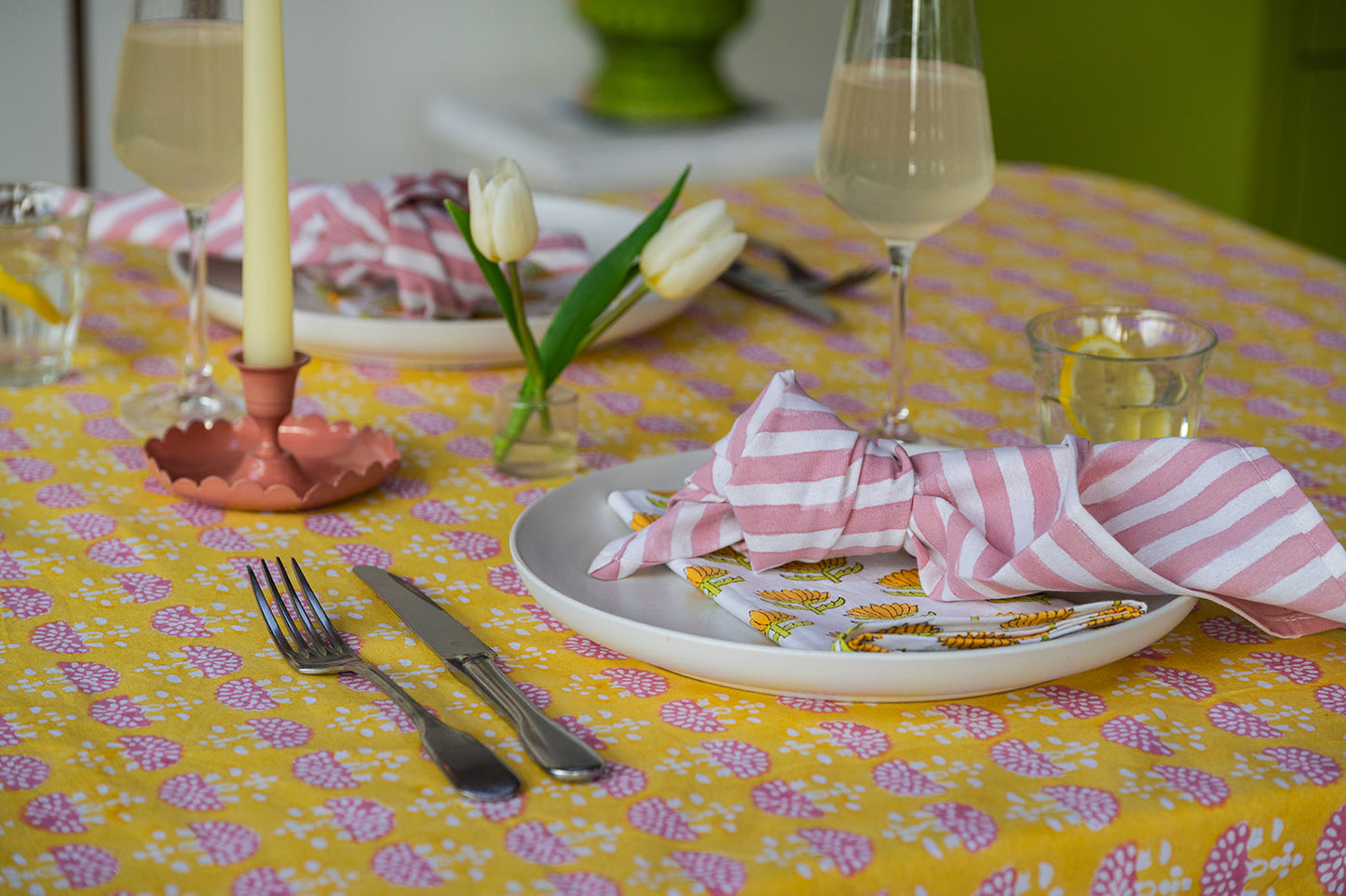 Easter table setting with floral tablecloth, eggs, and striped napkin.