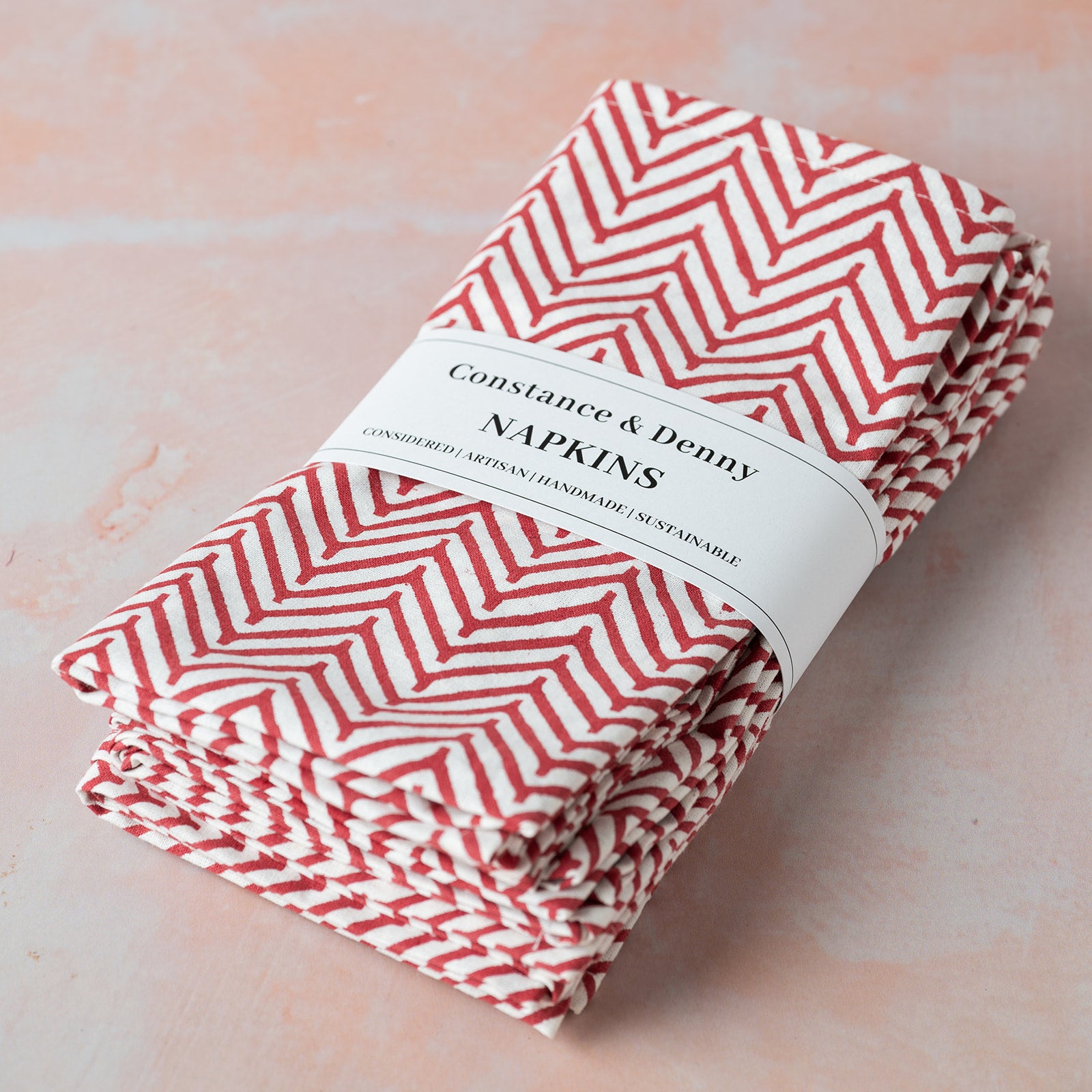Folded red and white chevron patterned napkins with a label on a light pink background