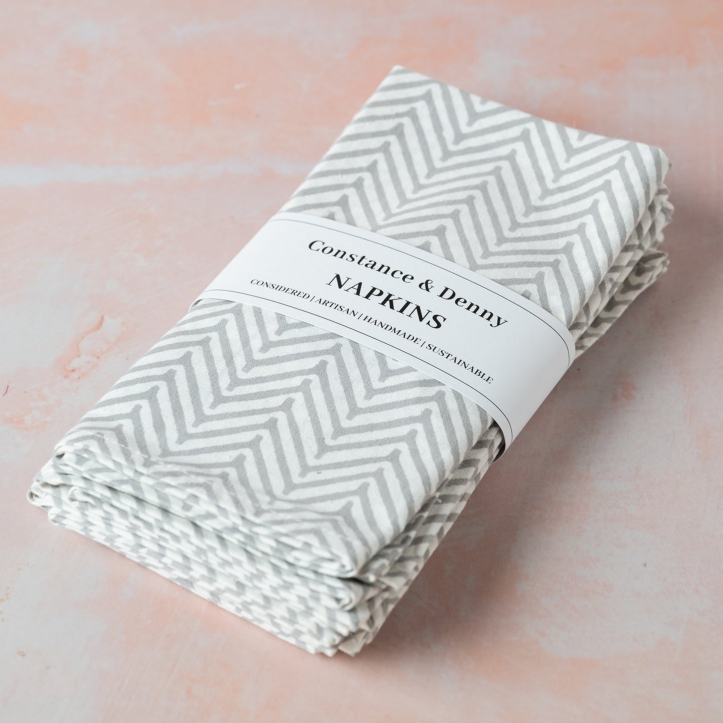 Folded napkins with a chevron pattern on a pink background