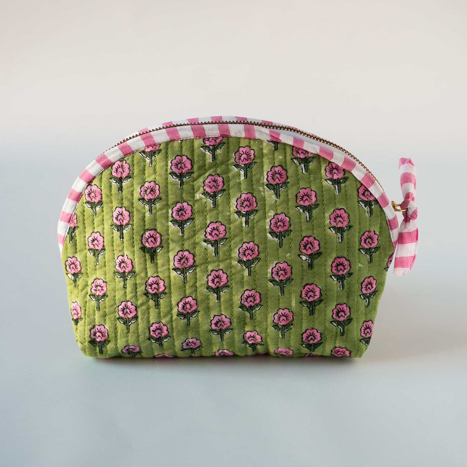 A quilted cosmetic pouch with a green background, pink rose pattern, and pink-and-white gingham trim, shown on a neutral light gray background.