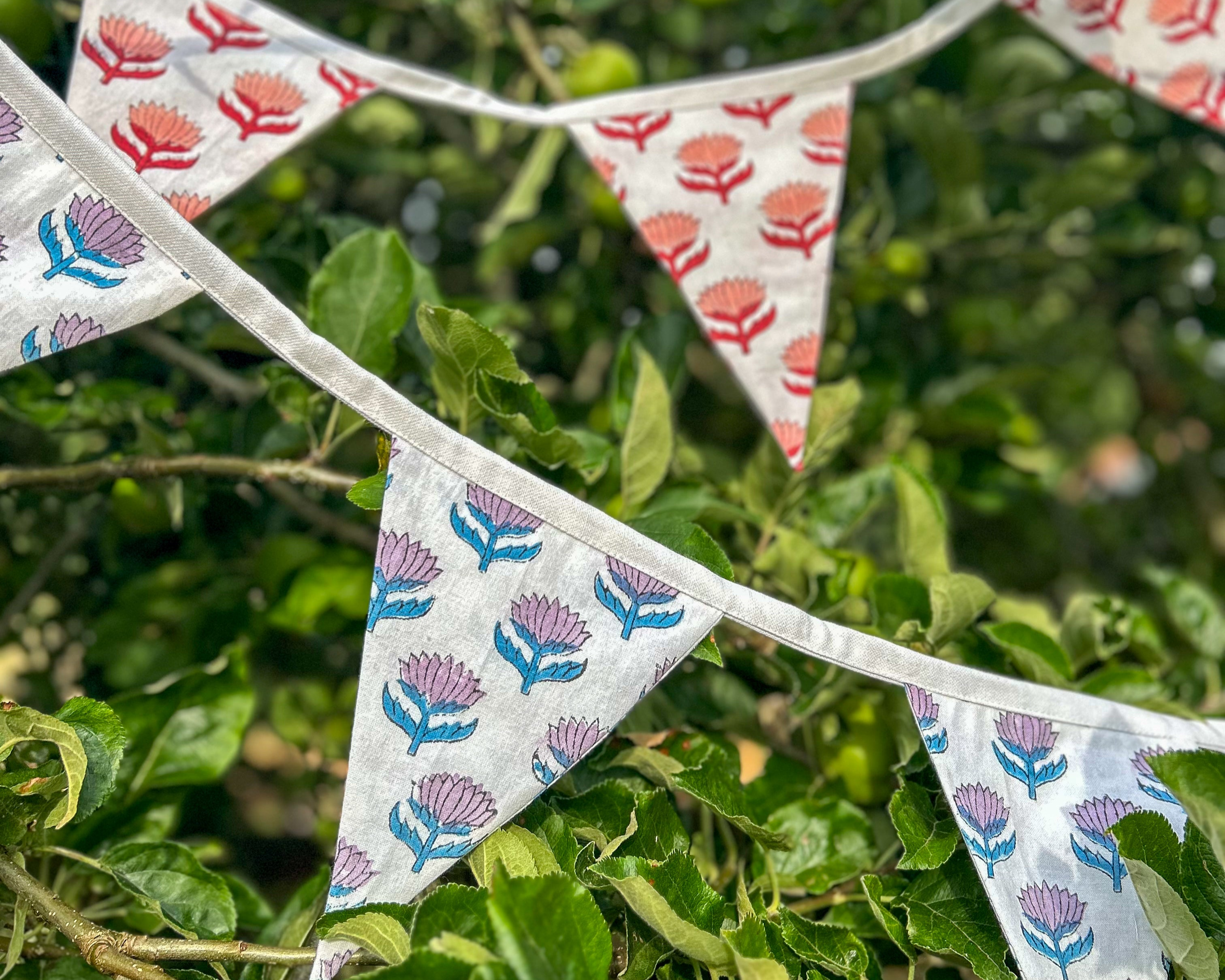 Decorative bunting with floral patterns hanging among green leaves