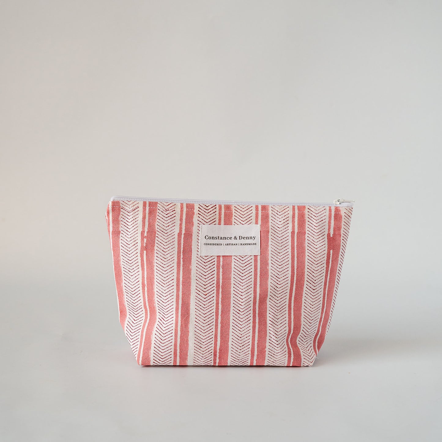 A rectangular zippered cosmetic pouch with a white and coral pink striped pattern, featuring a small white label on the front that reads 'Chic & Fashion'.