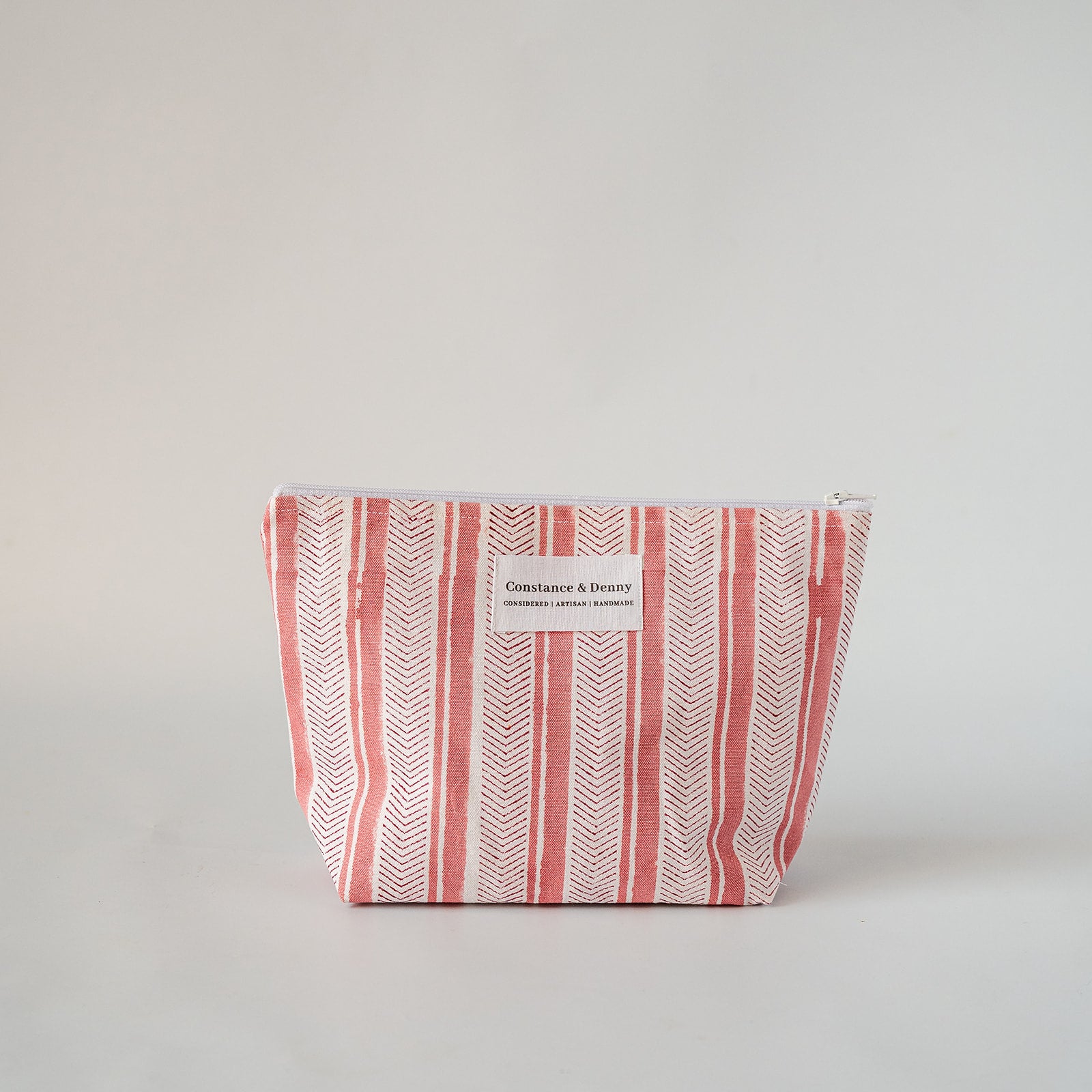 A rectangular zippered cosmetic pouch with a white and coral pink striped pattern, featuring a small white label on the front that reads 'Chic & Fashion'.