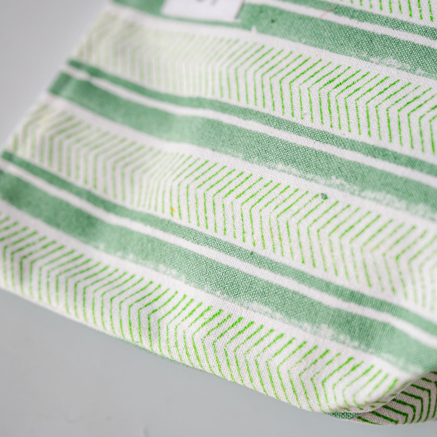 A close-up of a fabric item, likely a towel or cloth, featuring a green and white geometric chevron pattern.