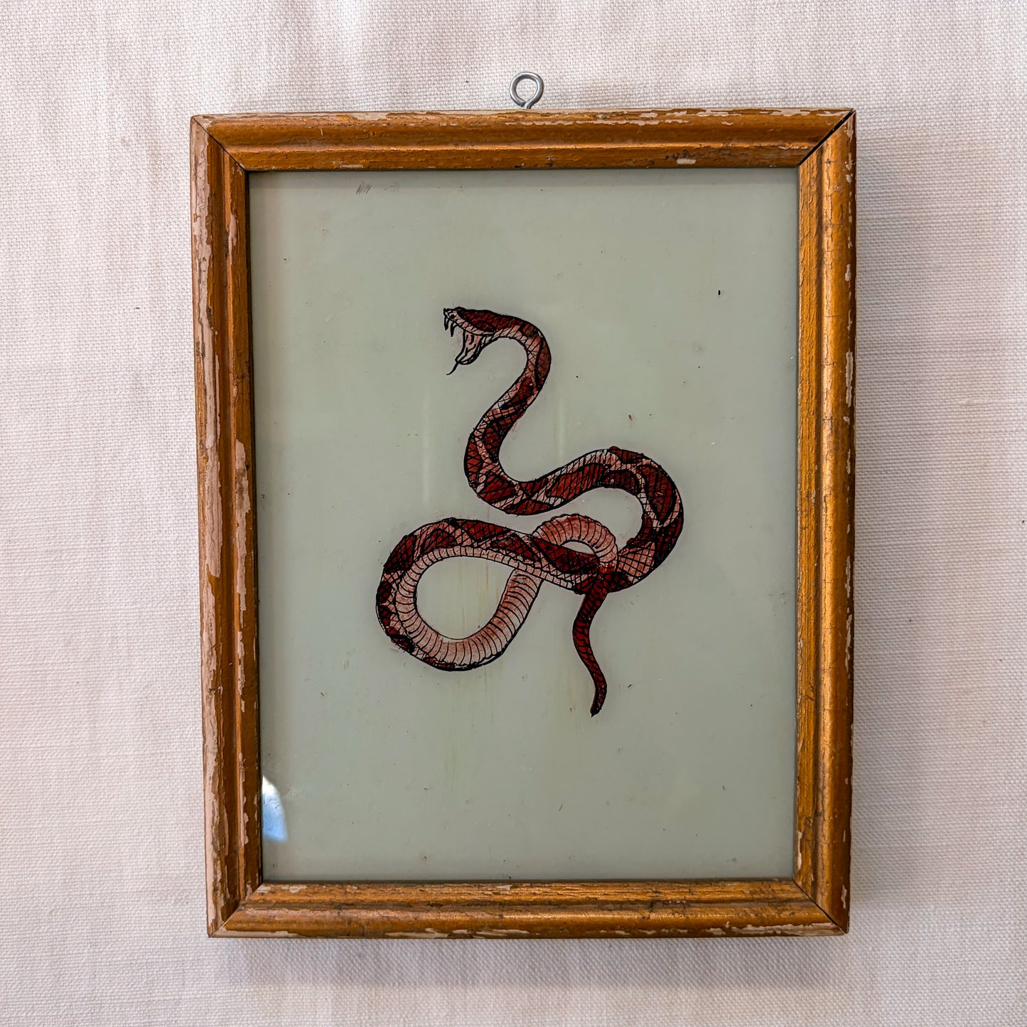 Framed artwork of a snake on a textured beige background