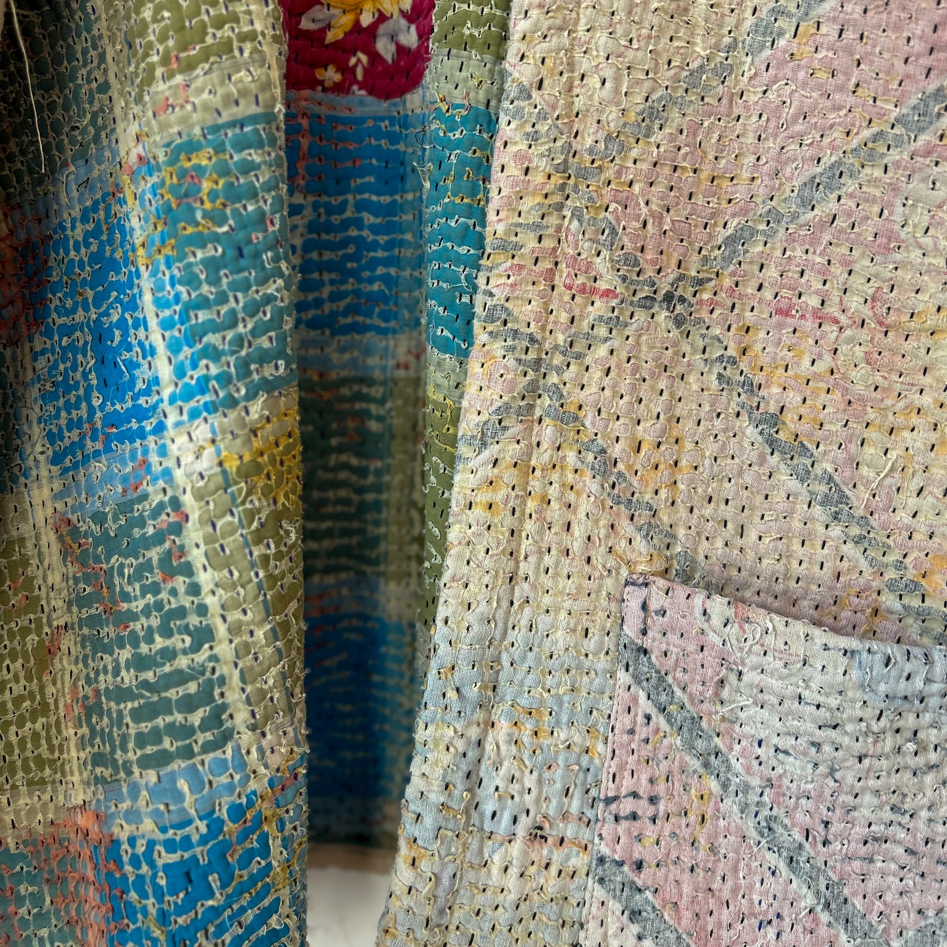 Close-up of textured fabric with a patchwork pattern in pastel colors. Vintage-kantha-jacket-handmade-unique-40-textured-inside