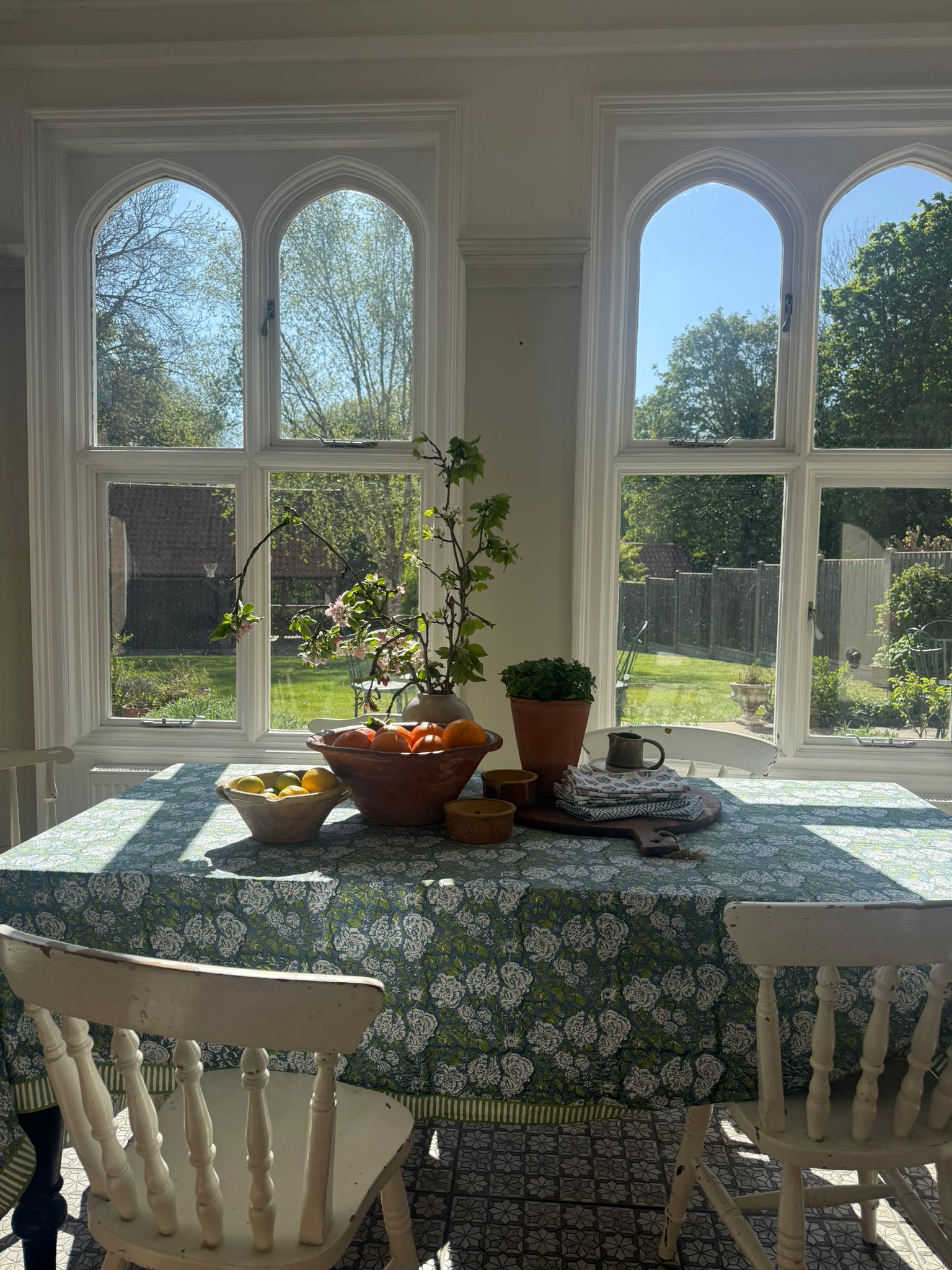 Dining room with a table set for breakfast, large windows showing a garden view.