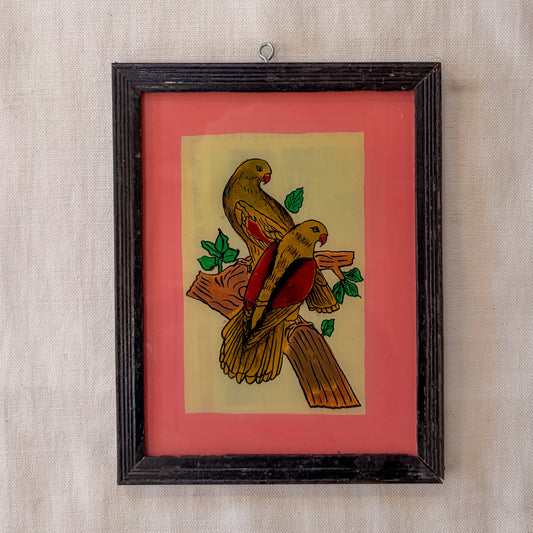 Framed artwork of two birds on a branch with a red background
