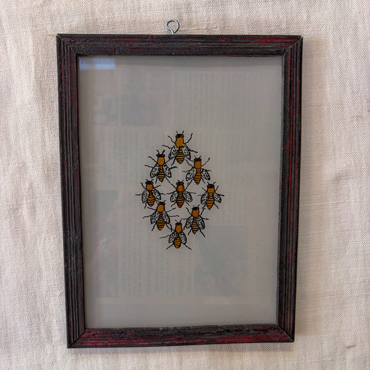 Framed artwork of bees on a textured wall