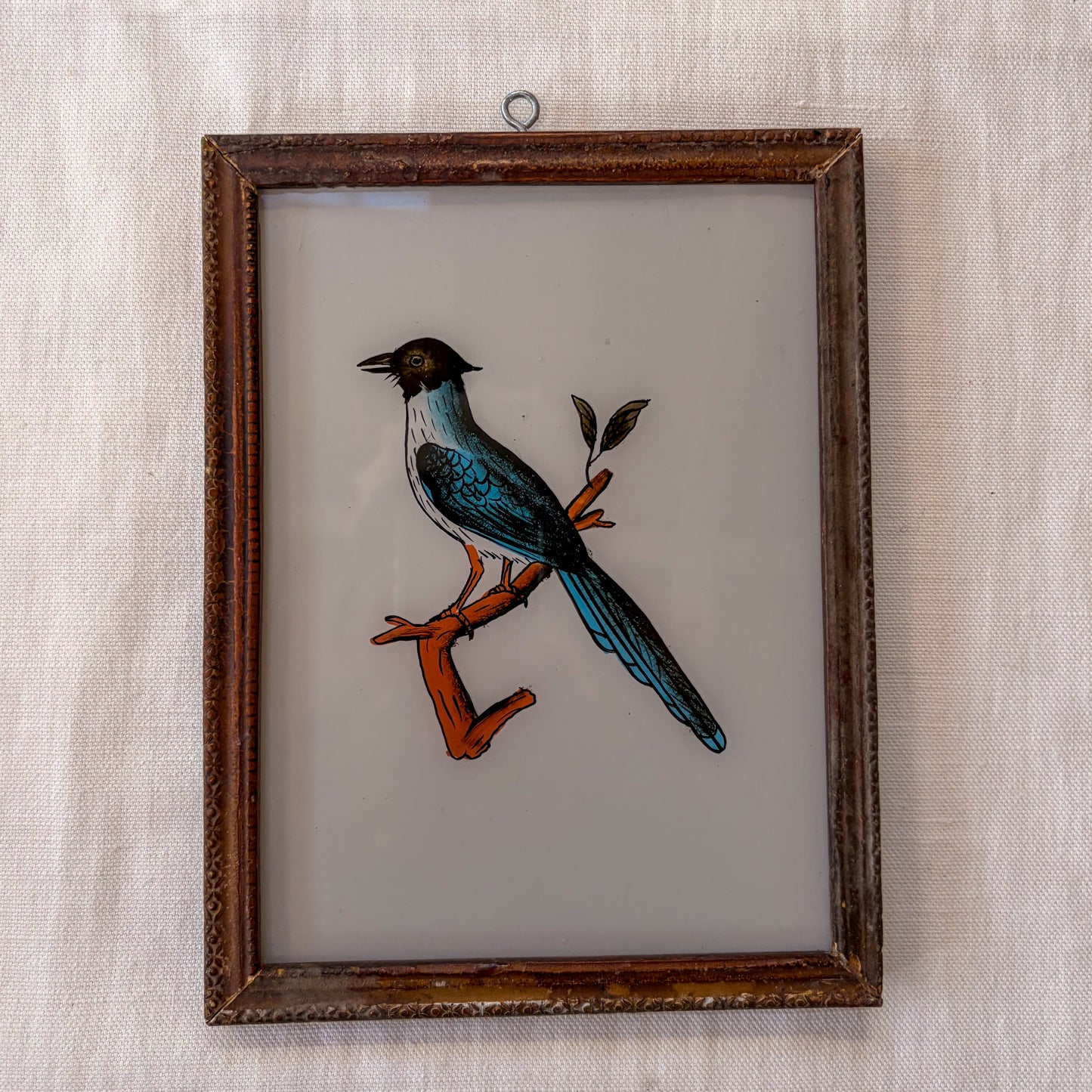 Framed artwork of a bird on a branch with a textured beige background