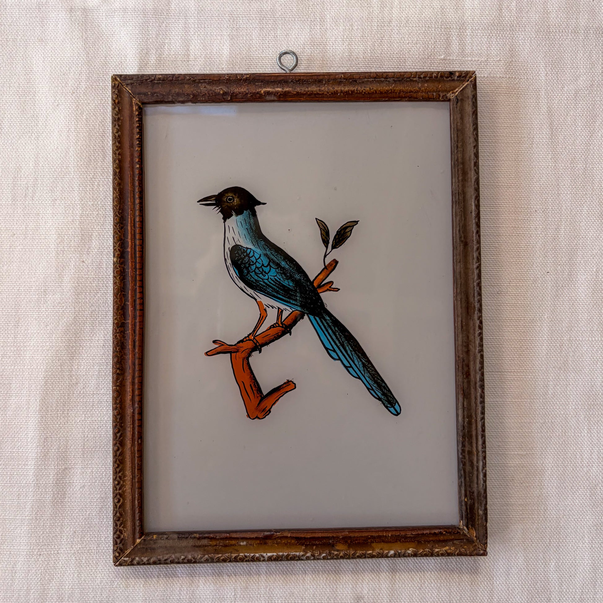 Framed artwork of a bird on a branch with a textured beige background