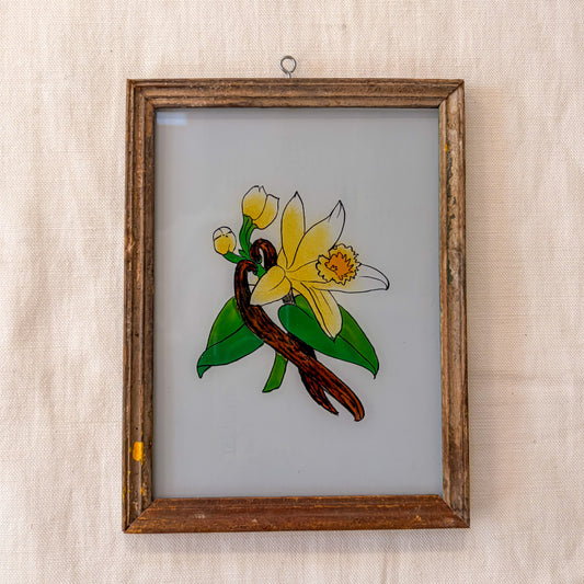 Framed stained glass artwork of a yellow flower and green leaves on a beige background