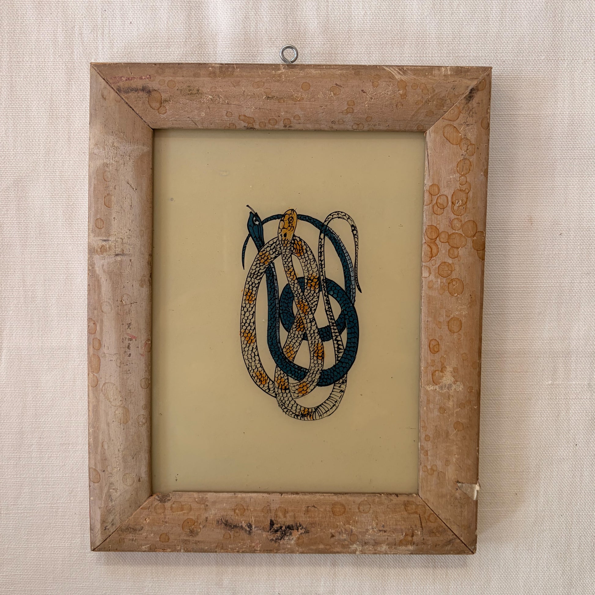 Framed artwork with intertwined snakes on a beige background