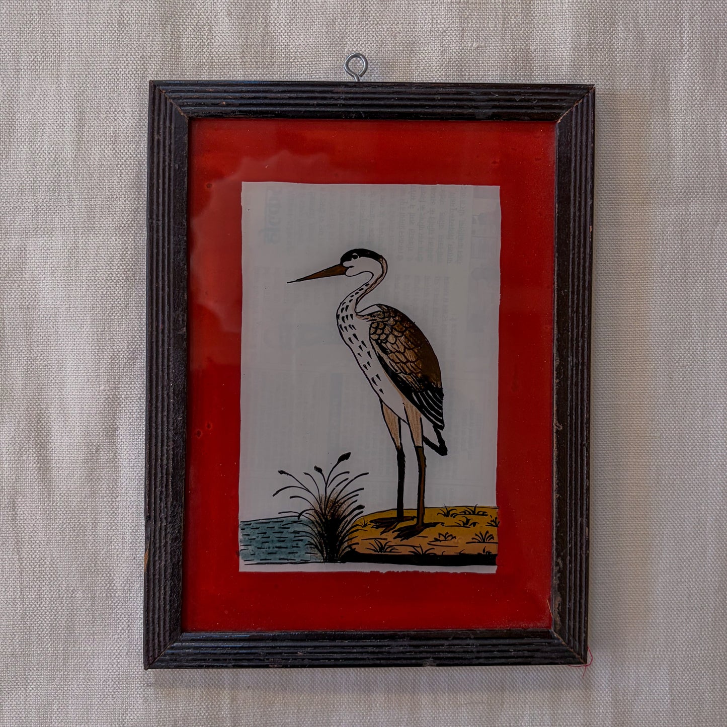 Framed artwork of a heron on a red background