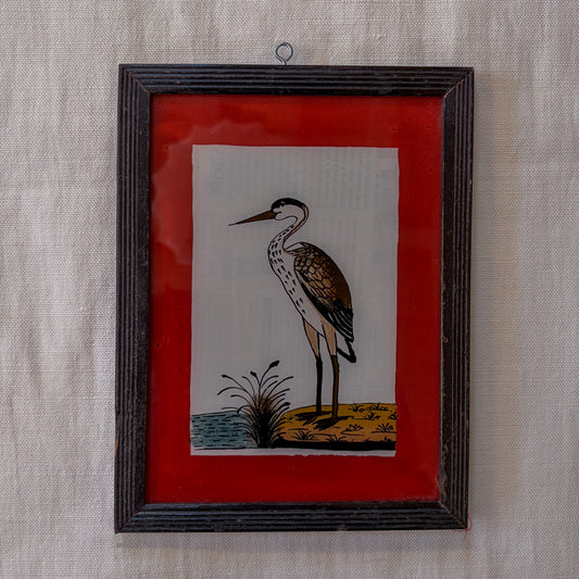Framed artwork of a heron on a red background