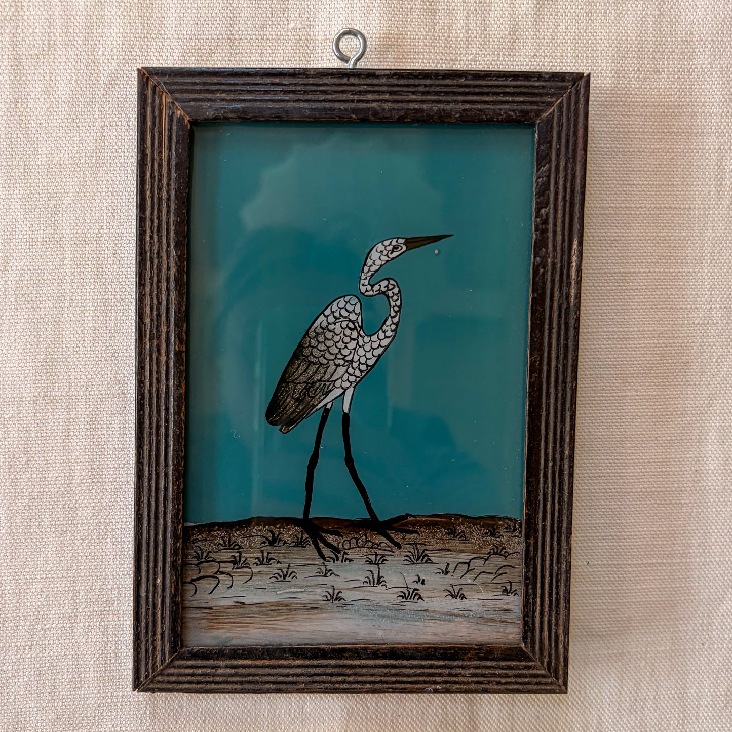 Framed artwork of a heron on a textured wall