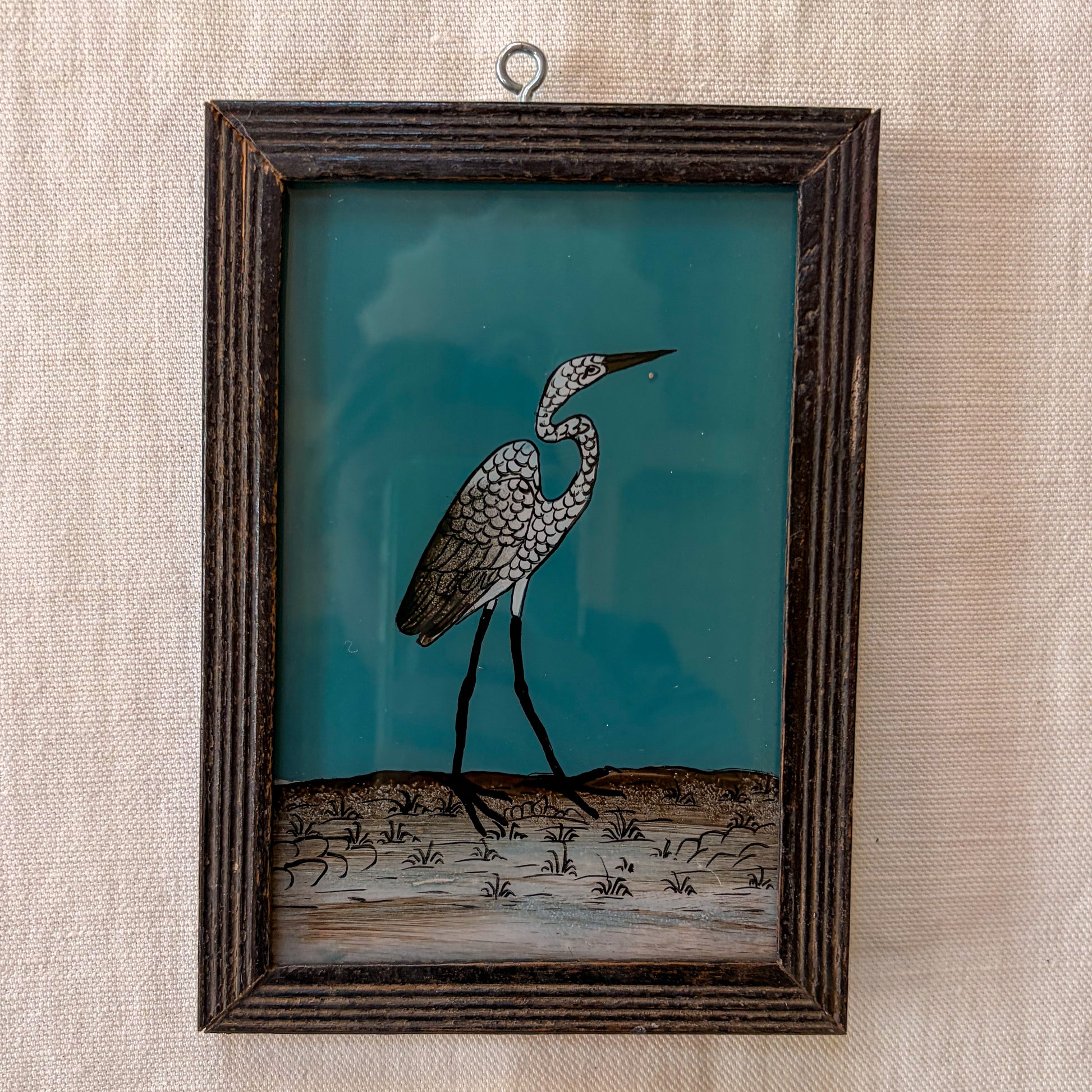 Framed artwork of a heron on a textured wall