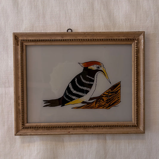 Framed illustration of a bird on a branch against a textured wall.