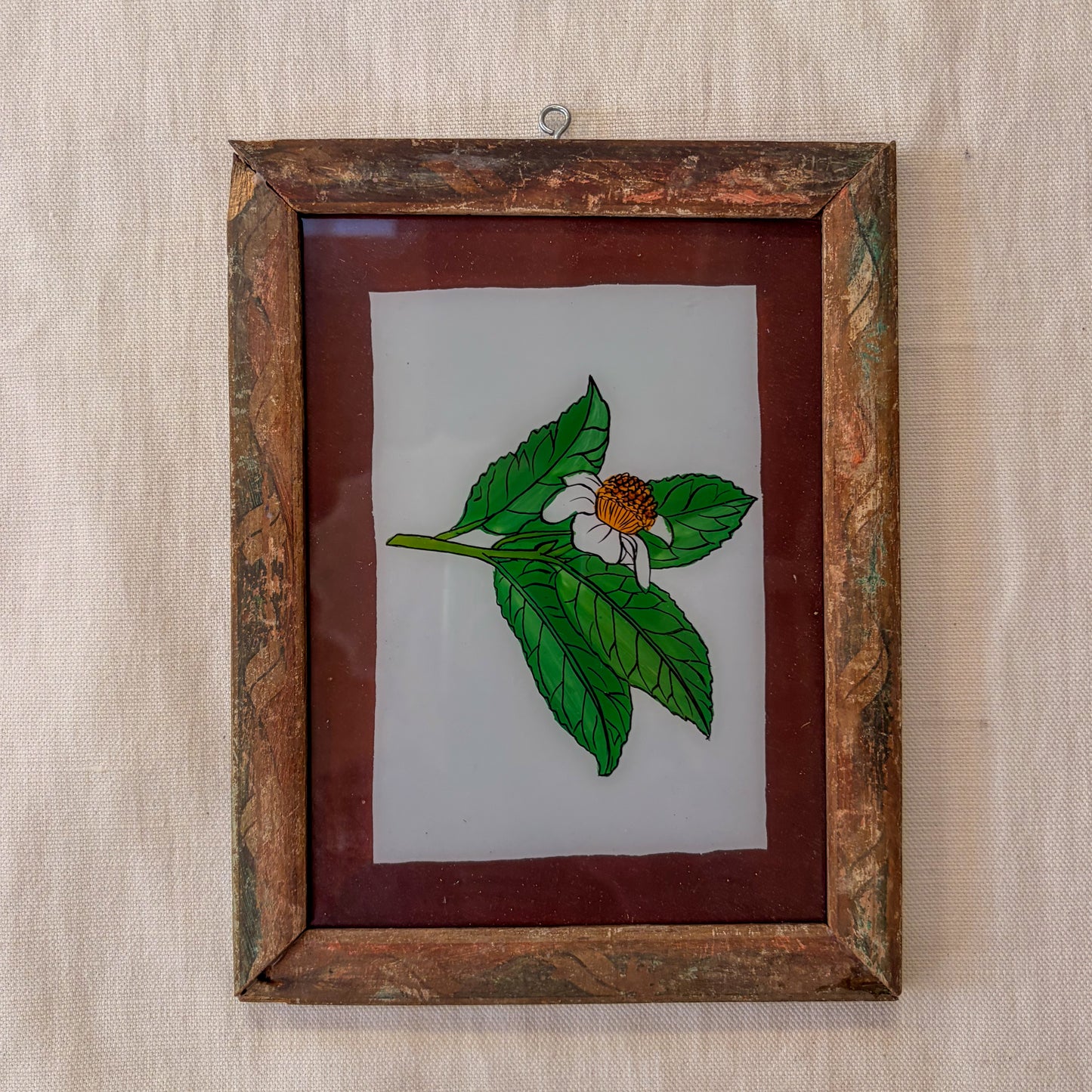 Framed artwork of a leaf and flower on a textured beige background