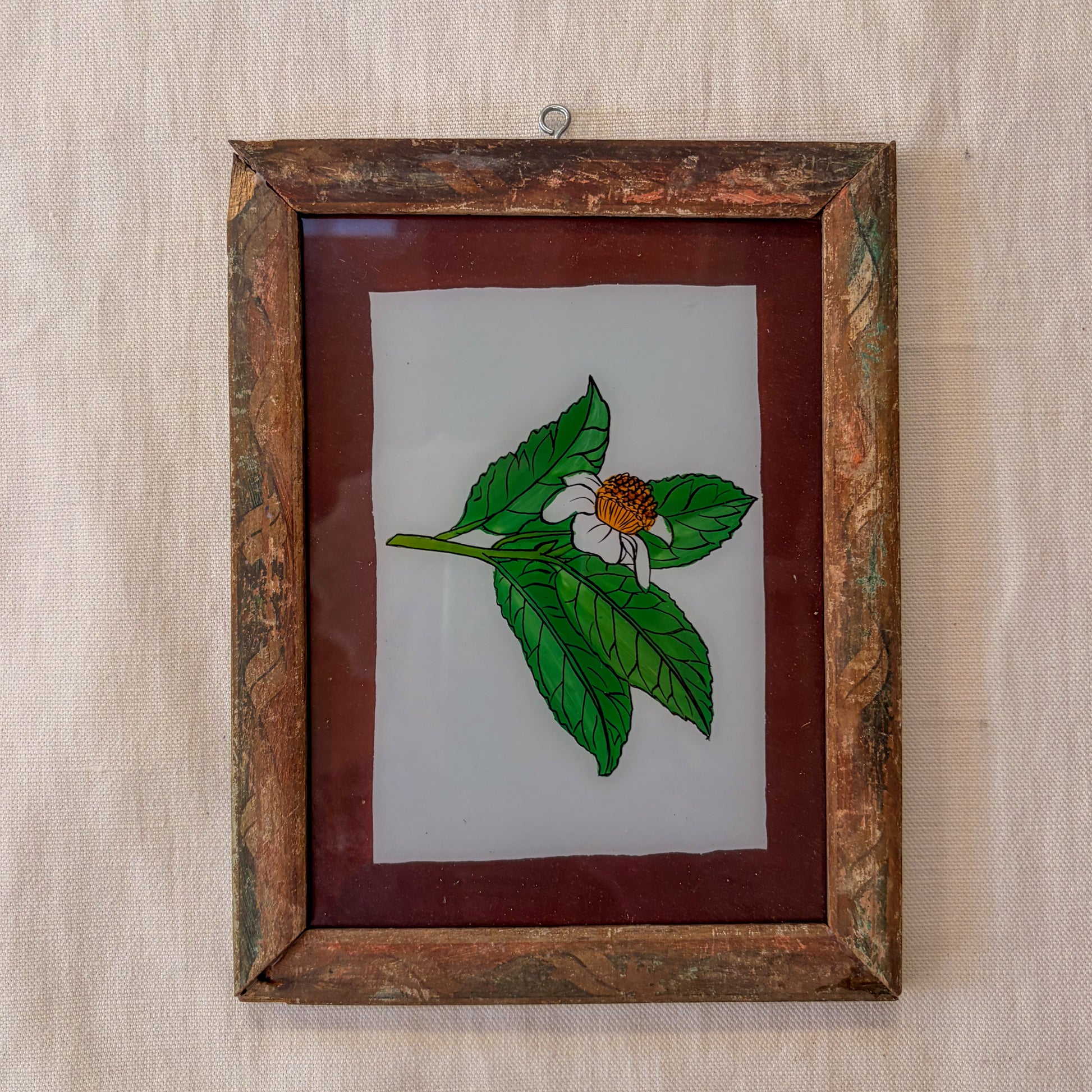 Framed artwork of a leaf and flower on a textured beige background