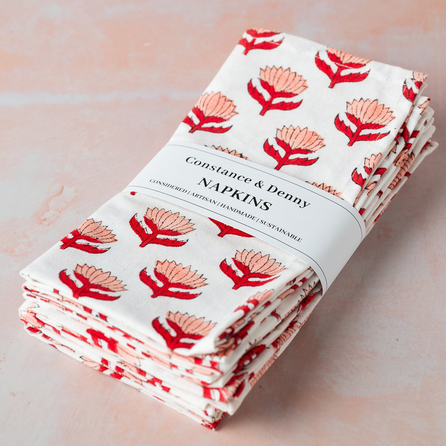 Pack of Constance & Denby napkins with floral design on a light pink background