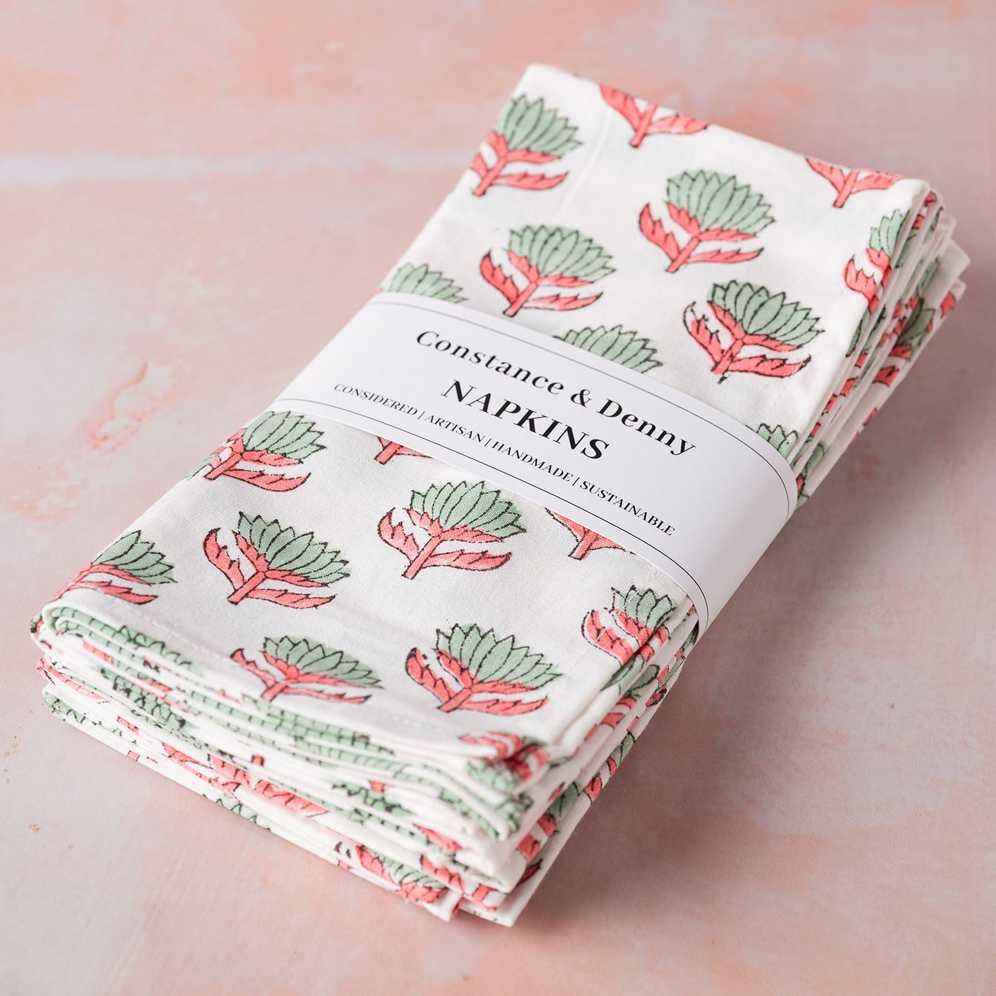 Folded napkins with a plant pattern on a pink surface