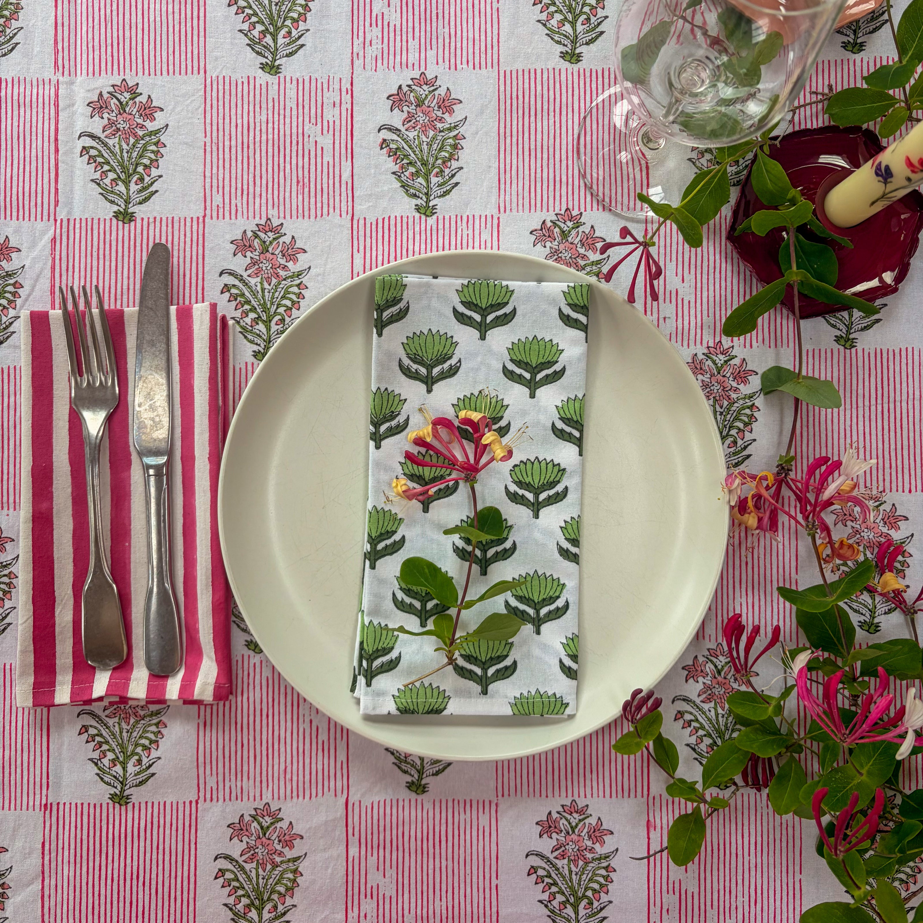 Table setting with floral-patterned tablecloth, plate, napkin, and cutlery.