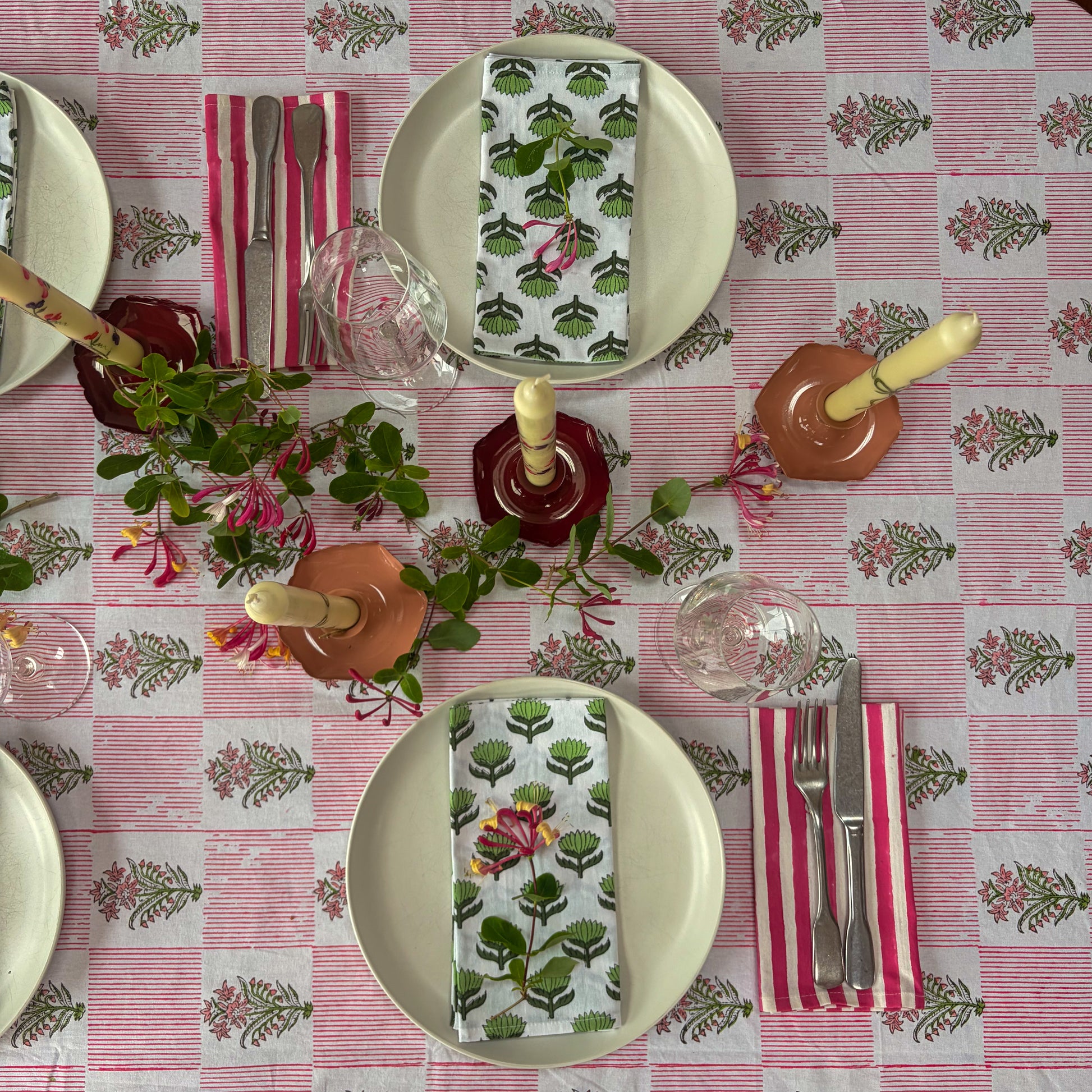 Dining table setting with floral tablecloth, plates, cutlery, and decorative napkins.