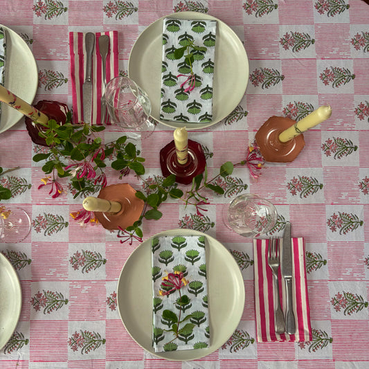 Dining table setting with floral tablecloth, plates, cutlery, and decorative napkins.