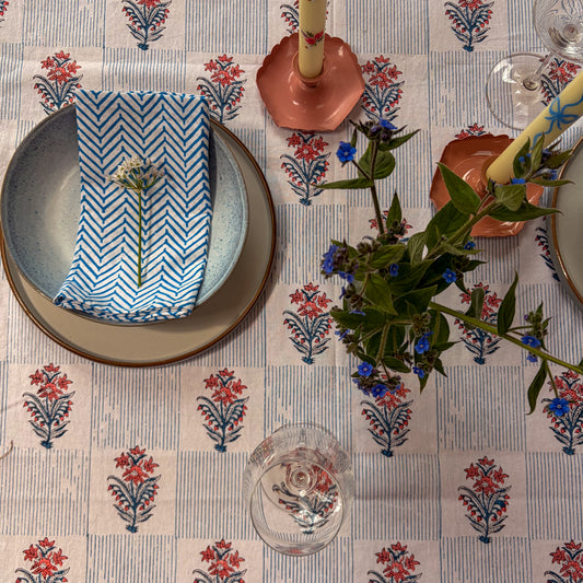 Table setting with floral tablecloth, plates, napkin, and candle holders.