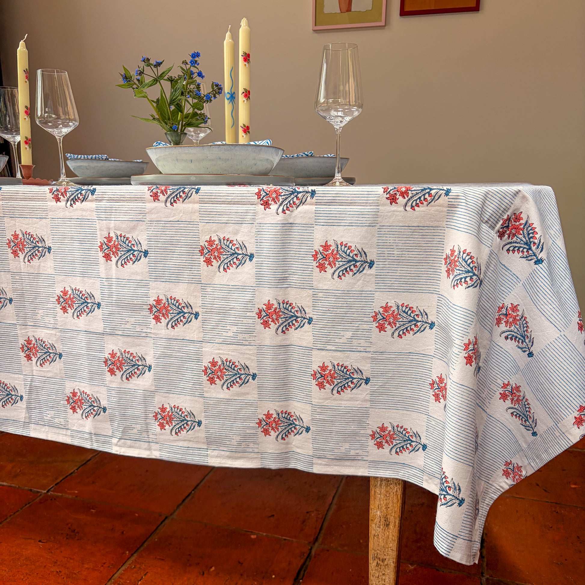 Tablecloth with floral pattern on a dining table with glasses and candles.