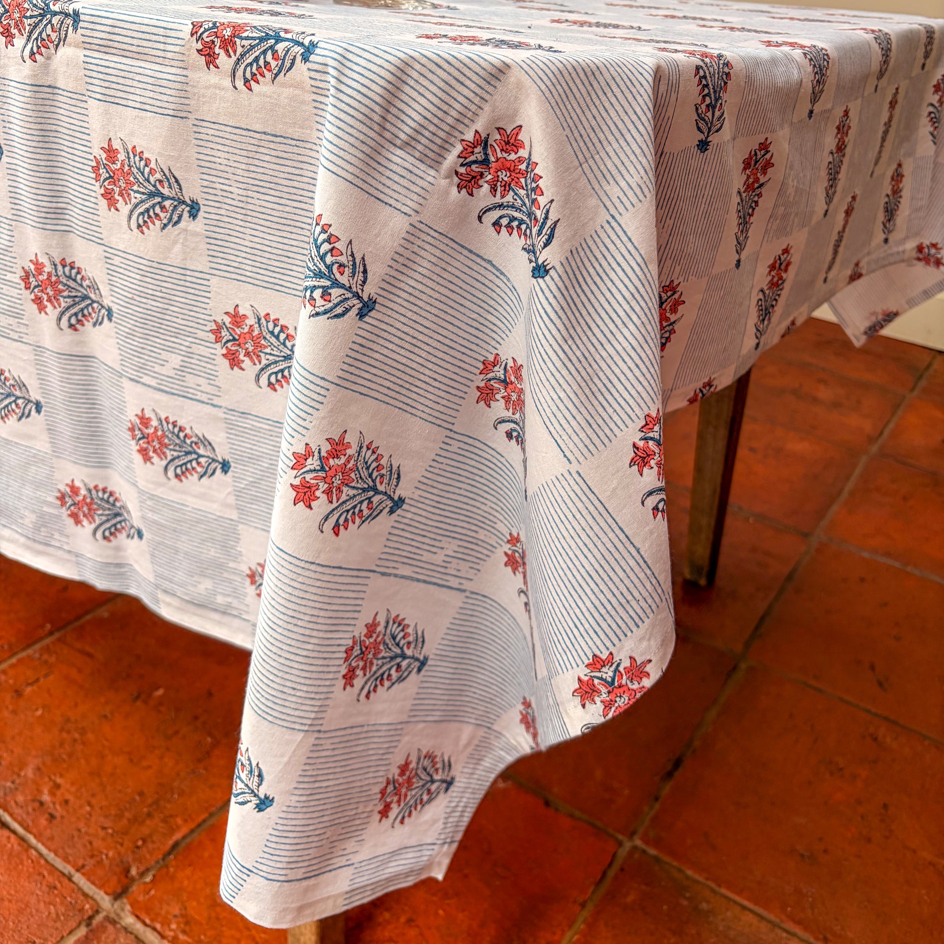 Floral patterned tablecloth on a wooden table with a tiled floor background