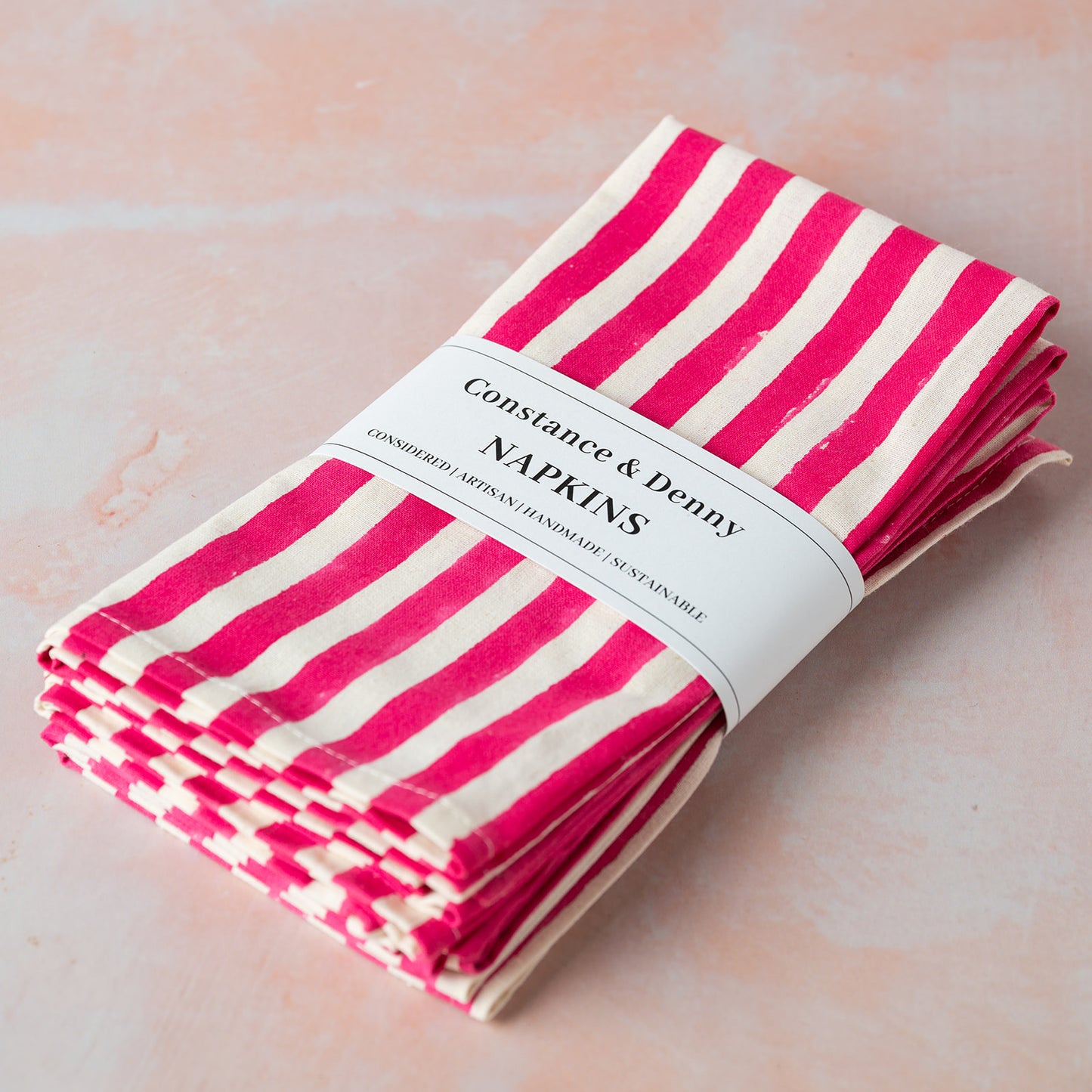 Pack of pink and white striped napkins with a label on a light background