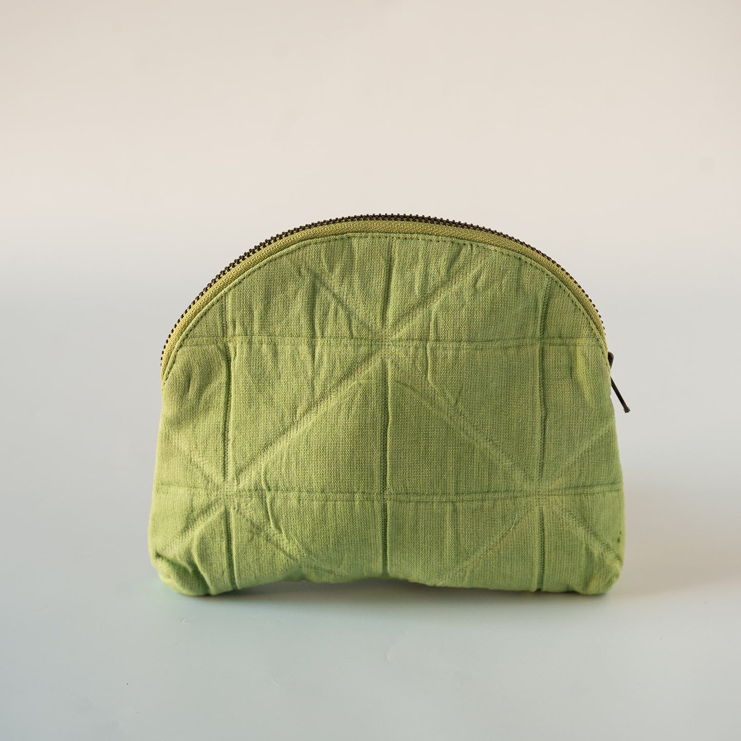 A light green quilted fabric zippered pouch with a geometric stitched pattern, shown on a plain light gray background.